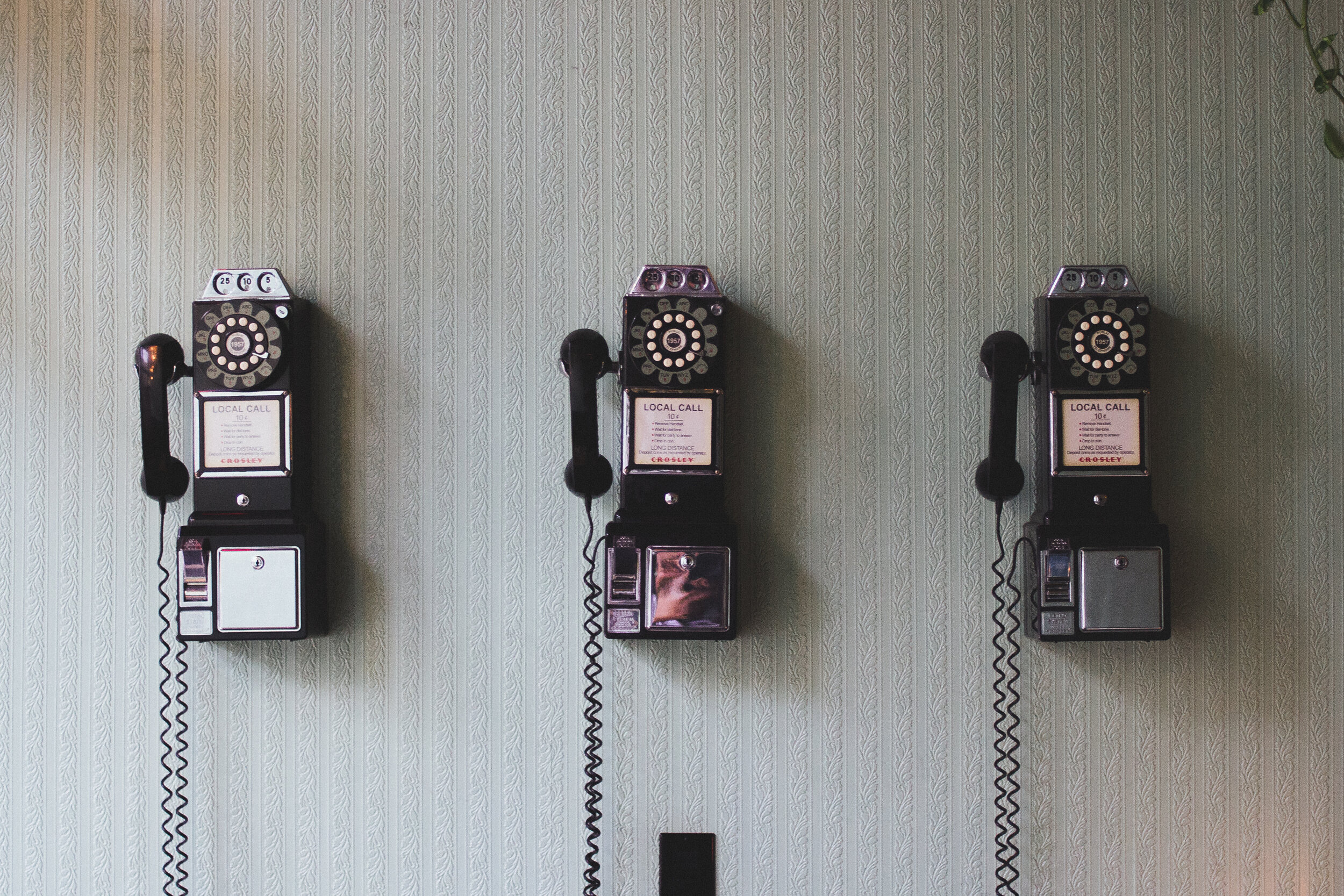 three old fashioned telephones on a striped wall