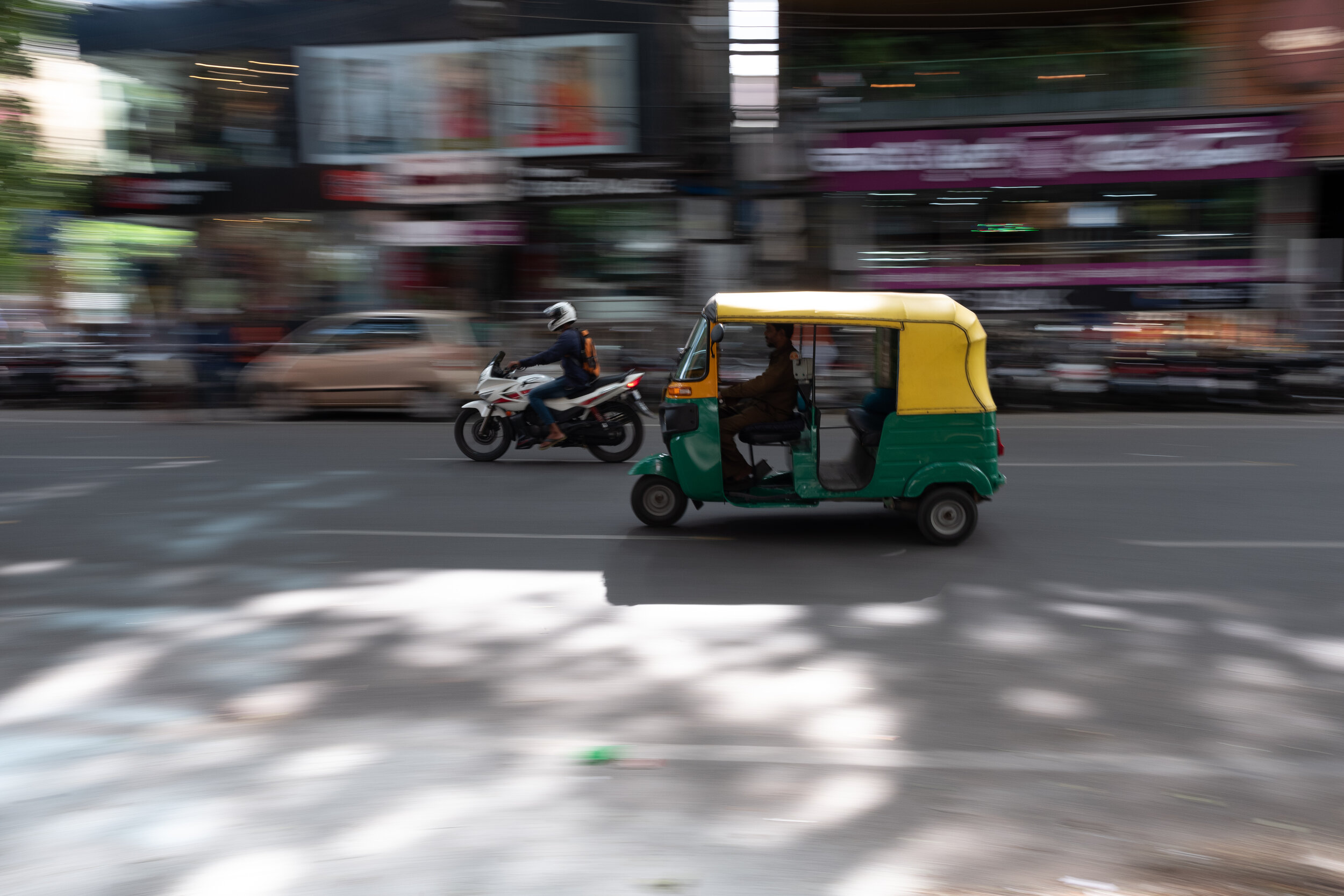 image of a rickshaw moving quickly down a street next to a motorcycle
