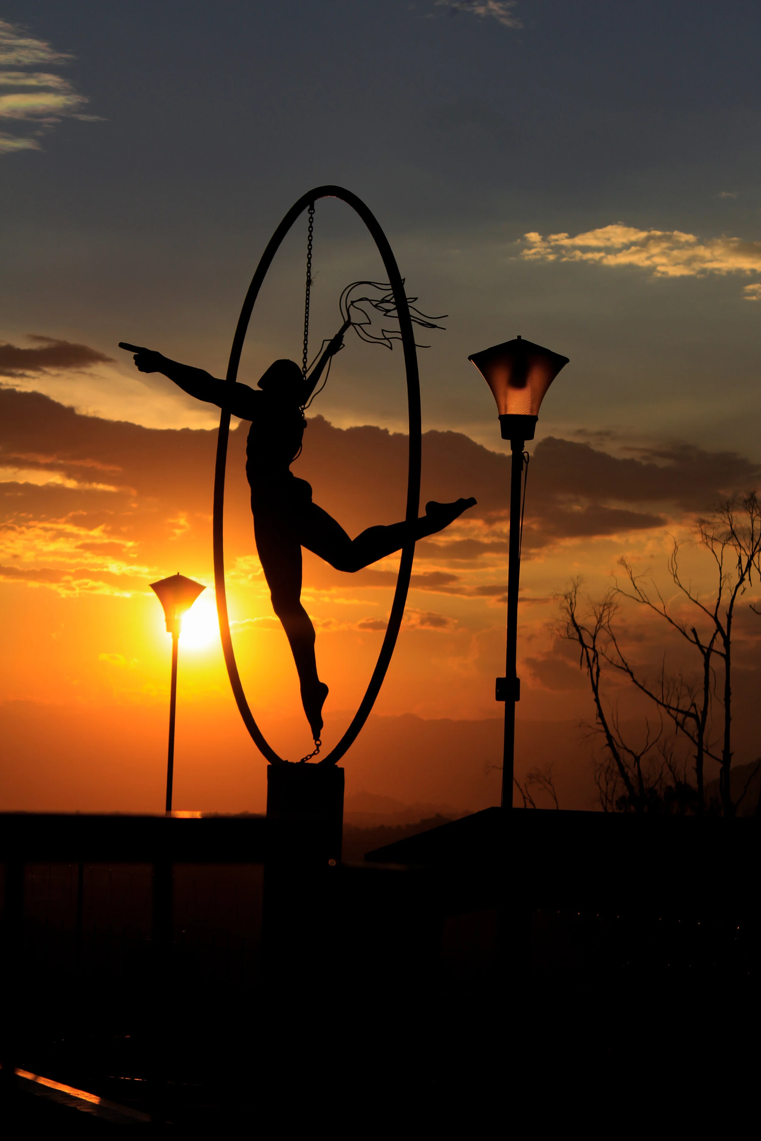 person inside a circle holding object in front of sunset