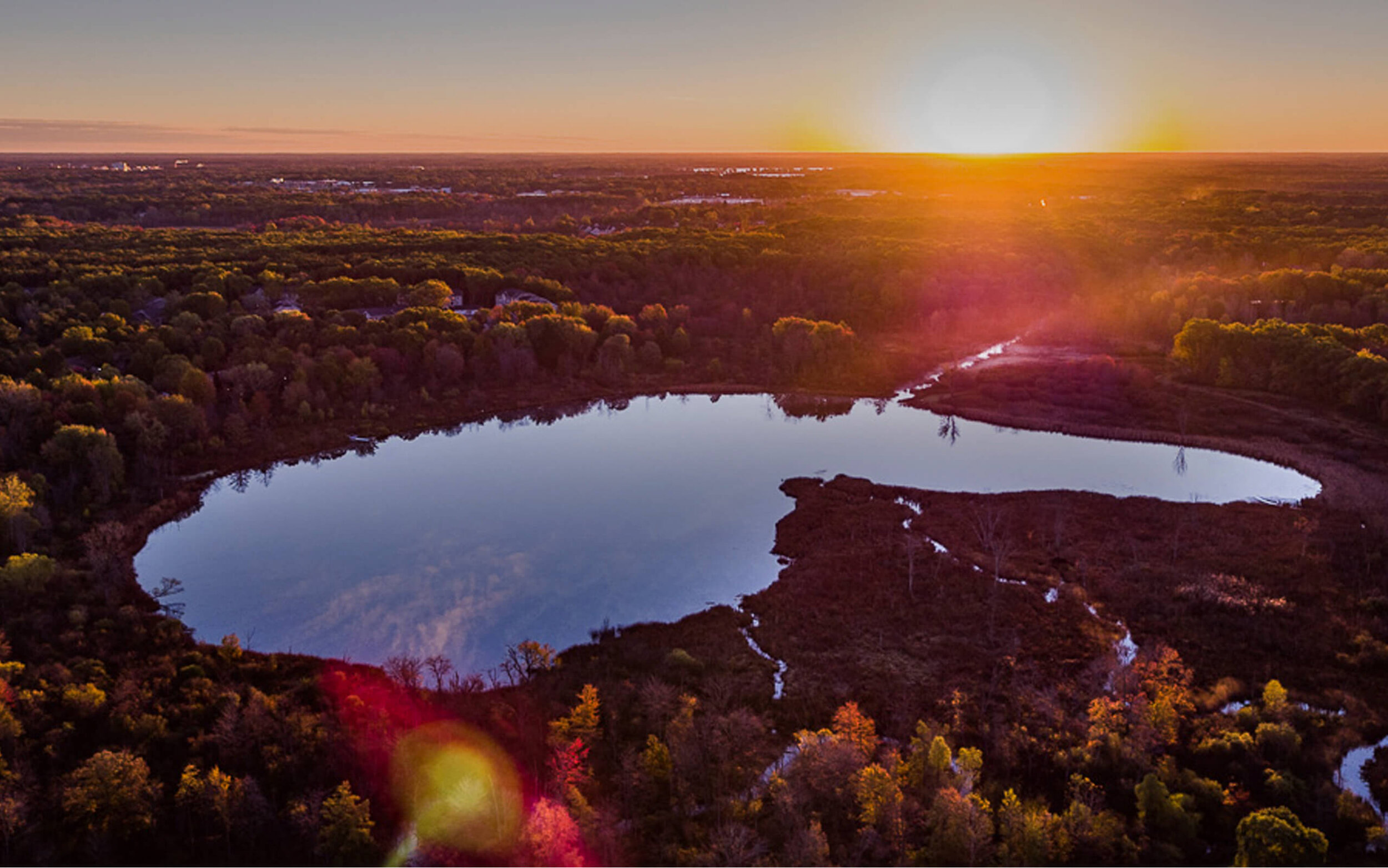 Aerial photo of lake and forest at sunrise/sunset.