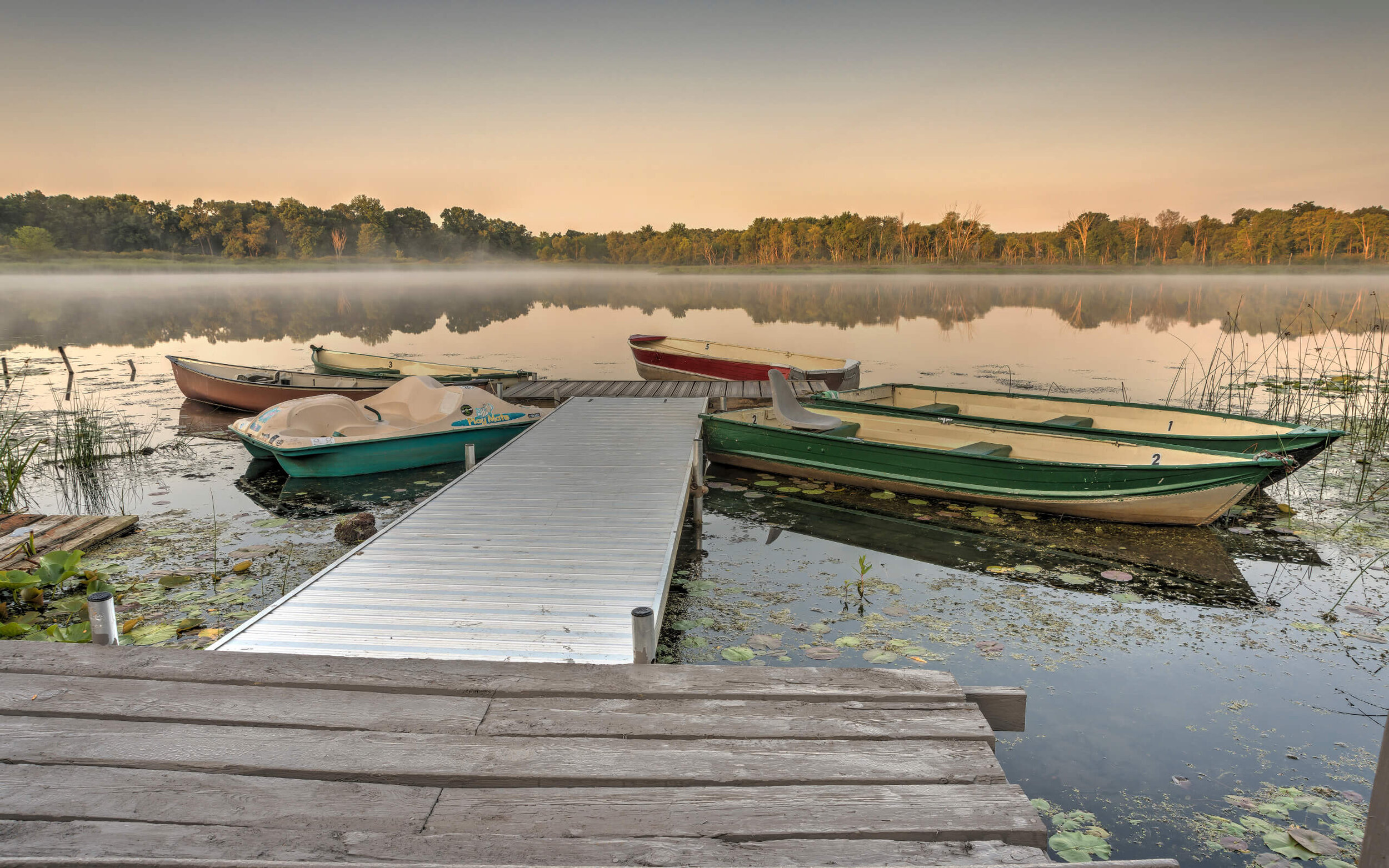 View of misty lake in morning from dock with boats.