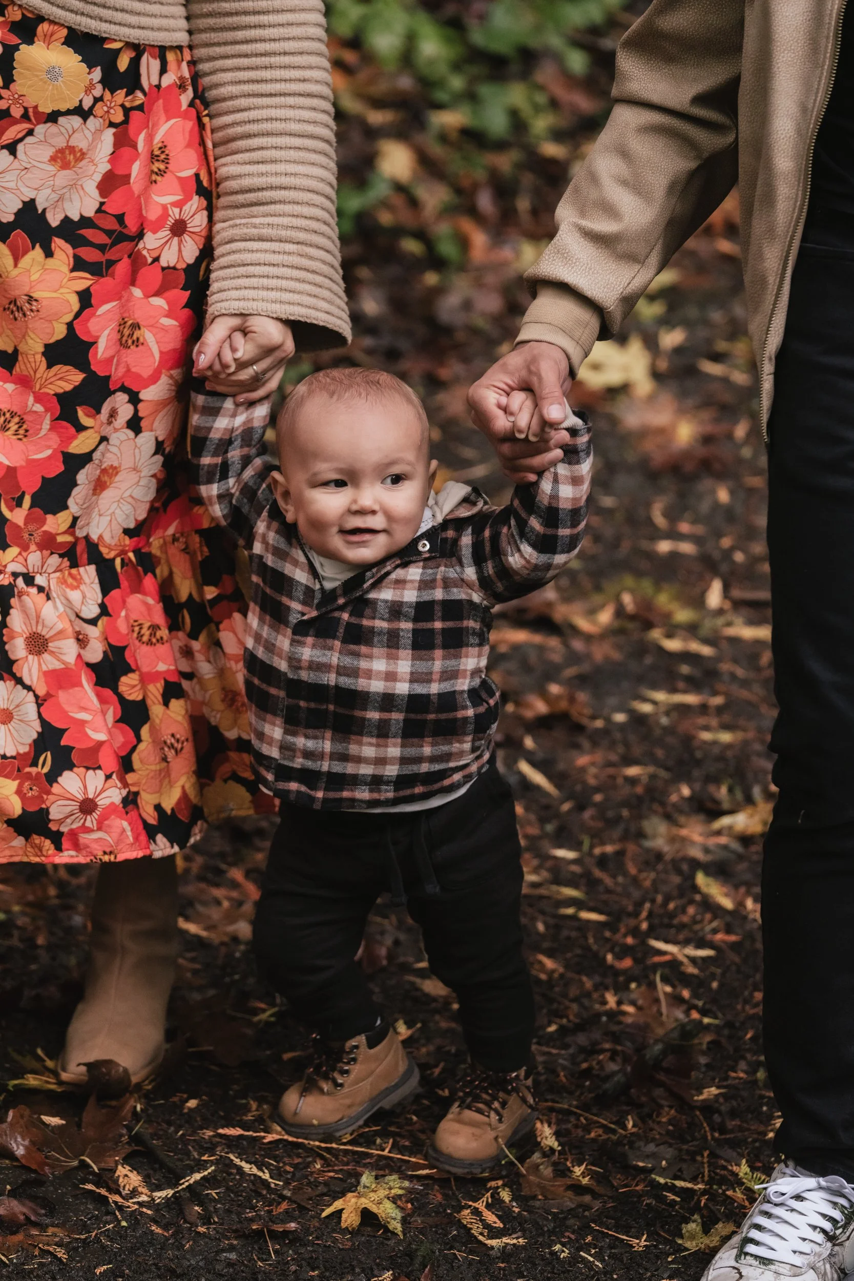 A small baby in boots hikes along a wet path.