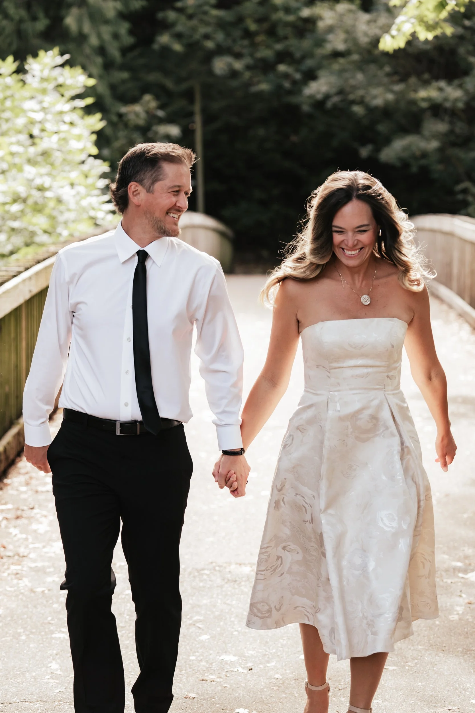 A cute couple laugh as they run down a walking bridge in George Rogers Park.