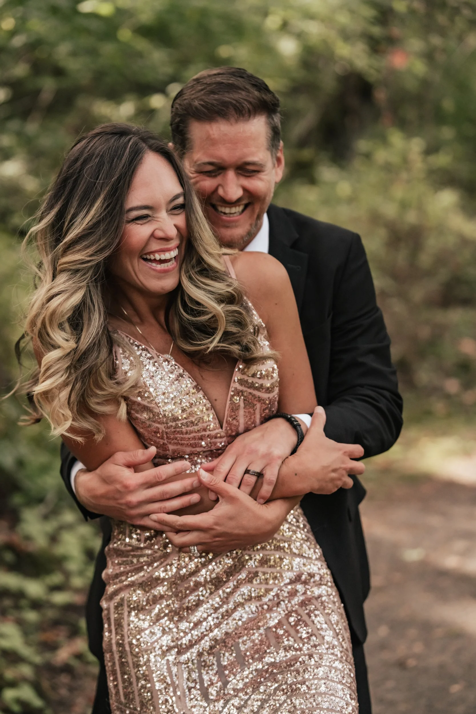 A happy man surprises his date with a hug in the forest.