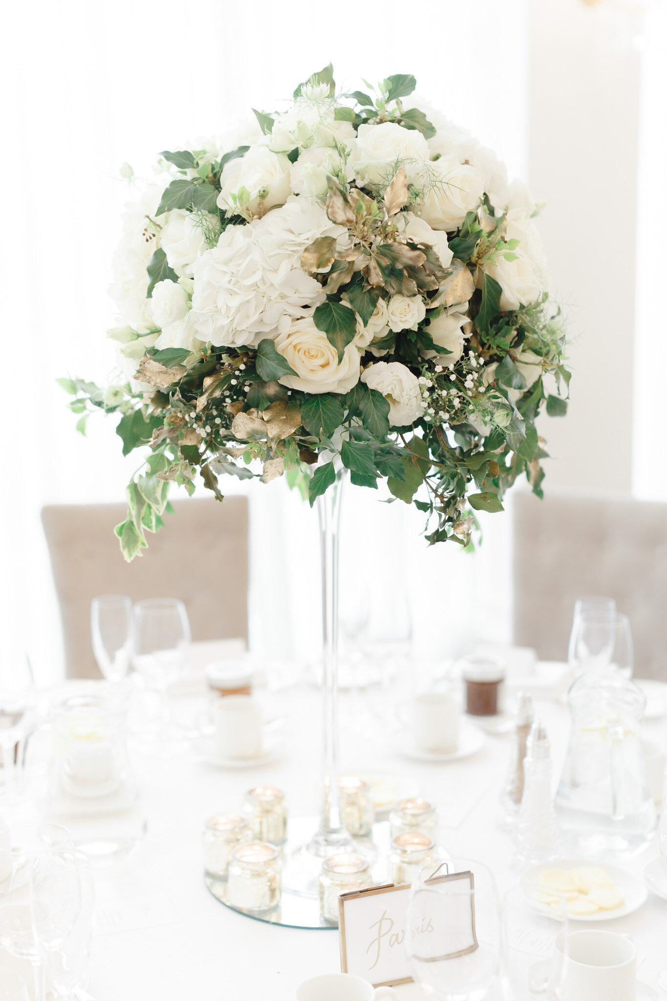 Tall wedding table arrangement set on a mirror plate and tea light candle