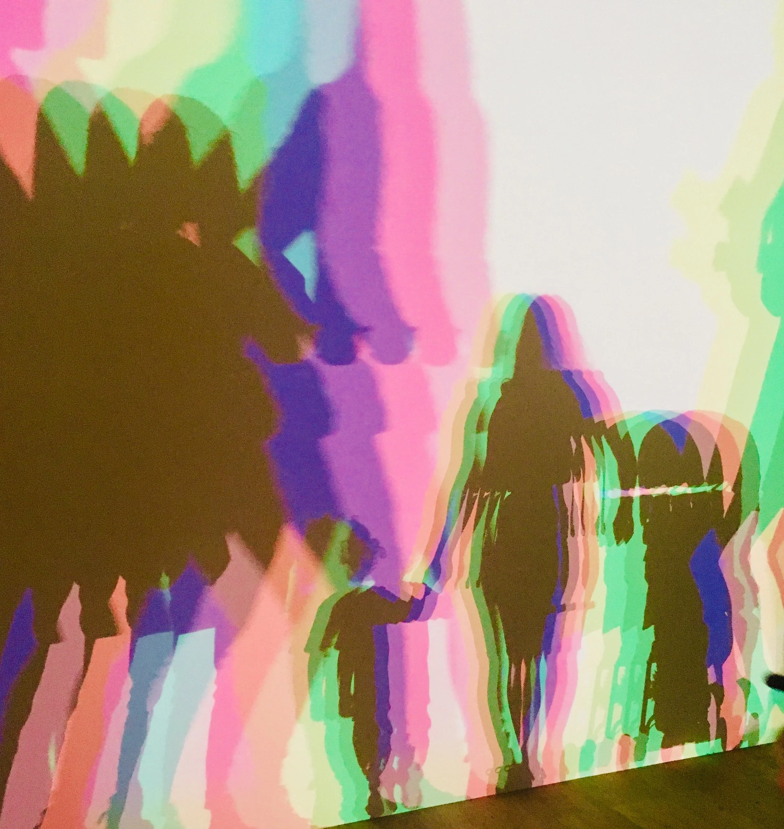 Colorful abstract pattern with overlapping rainbow-colored shapes and silhouettes of trees along the bottom edge.