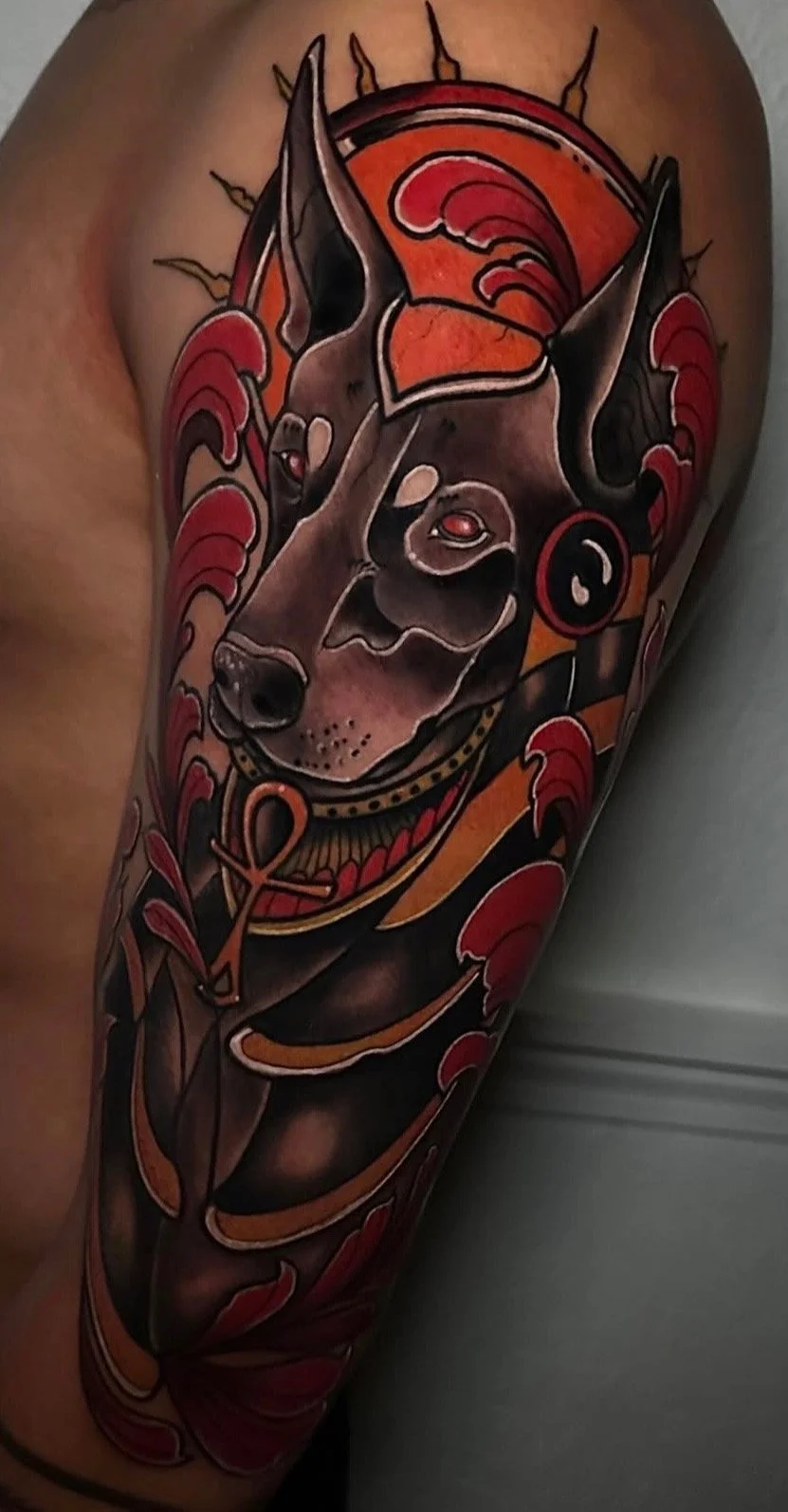 Tattoo of a dog with geometric and colorful design elements, including red, orange, black, and gray shades.