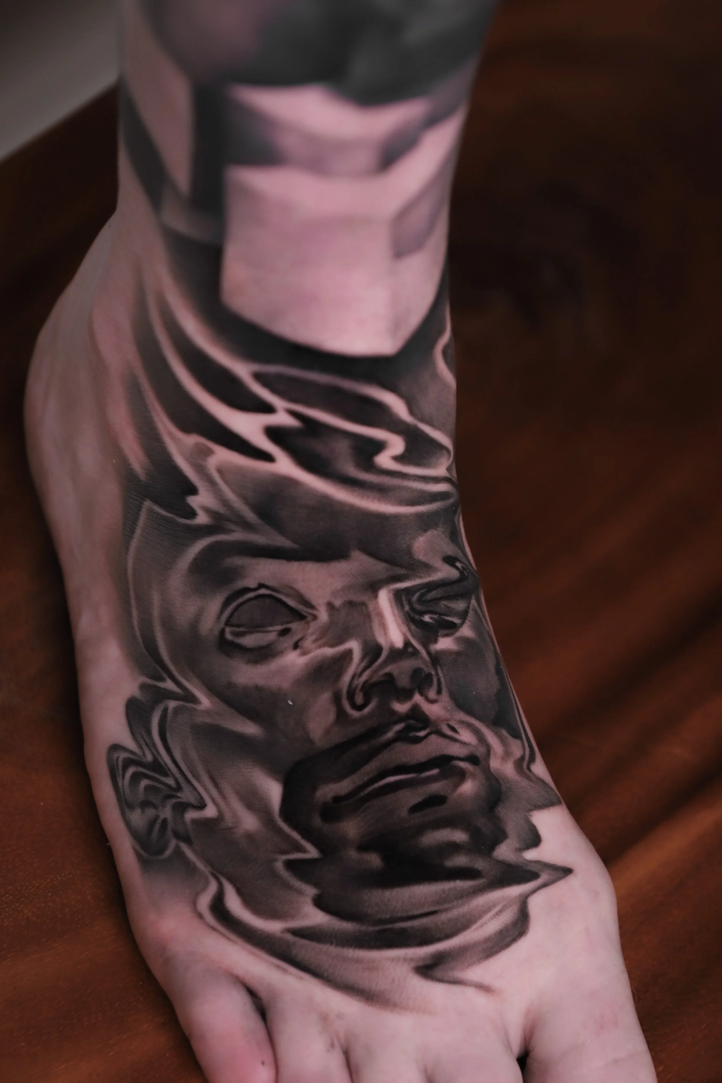 Close-up of a tattooed arm with a detailed black and gray portrait of a woman wearing a headband.