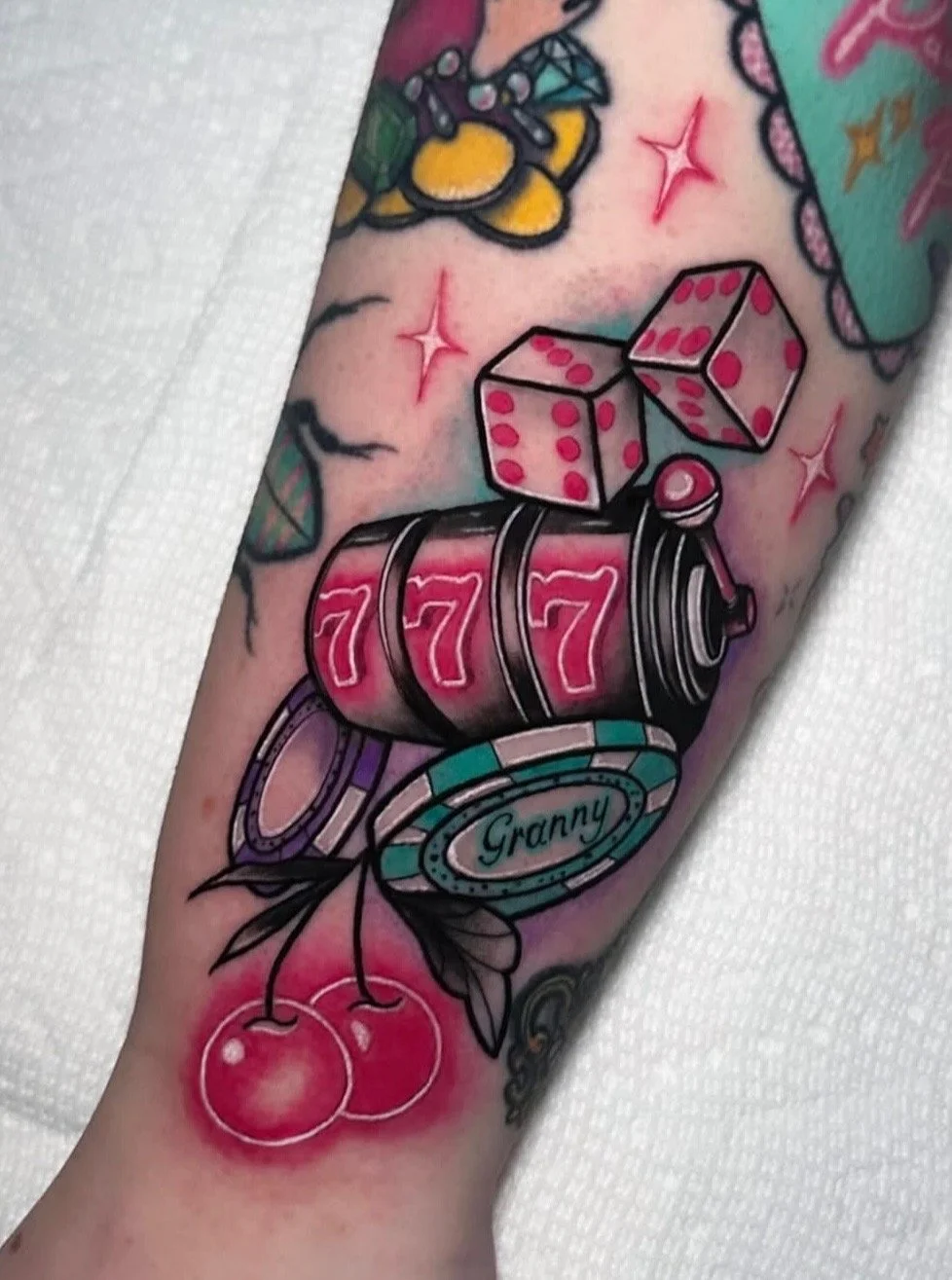 Colorful tattoo featuring a slot machine with three sevens, dice showing five and three, cherries, stars, and protective elements like a band and leaves, with the word 'Granny' on a bezel.
