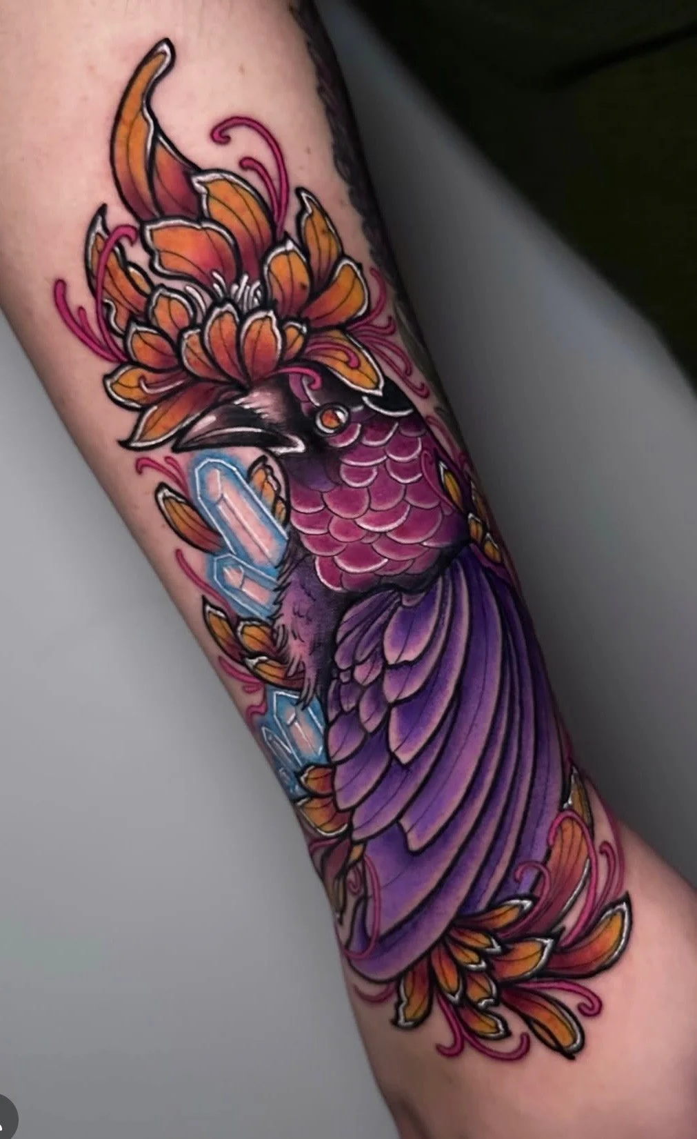 Colorful tattoo of a butterfly with pink, purple, orange, and black details on a person's arm.
