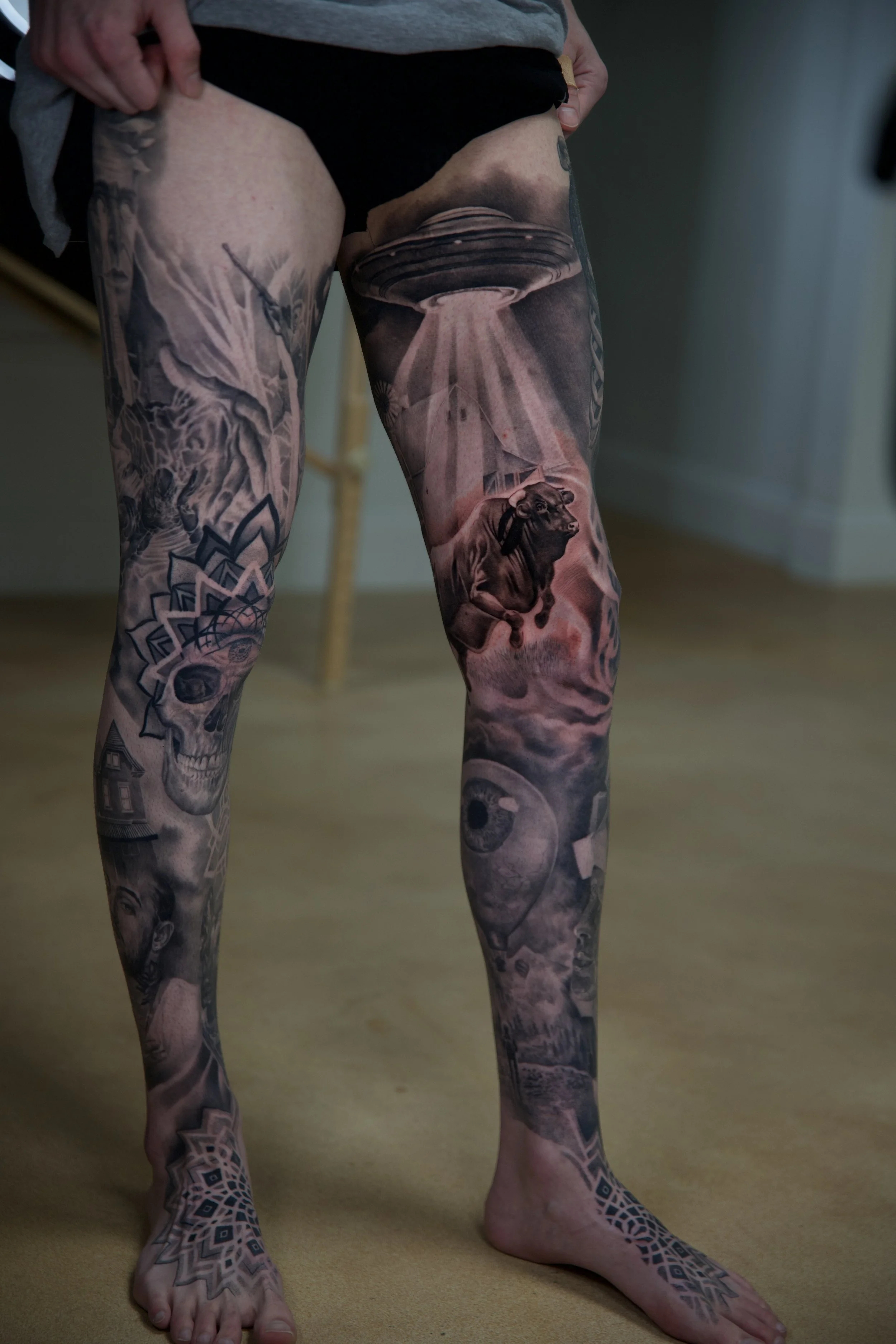 Person with full leg and foot tattoos featuring various intricate designs, including a skull, a lion, and geometric patterns.