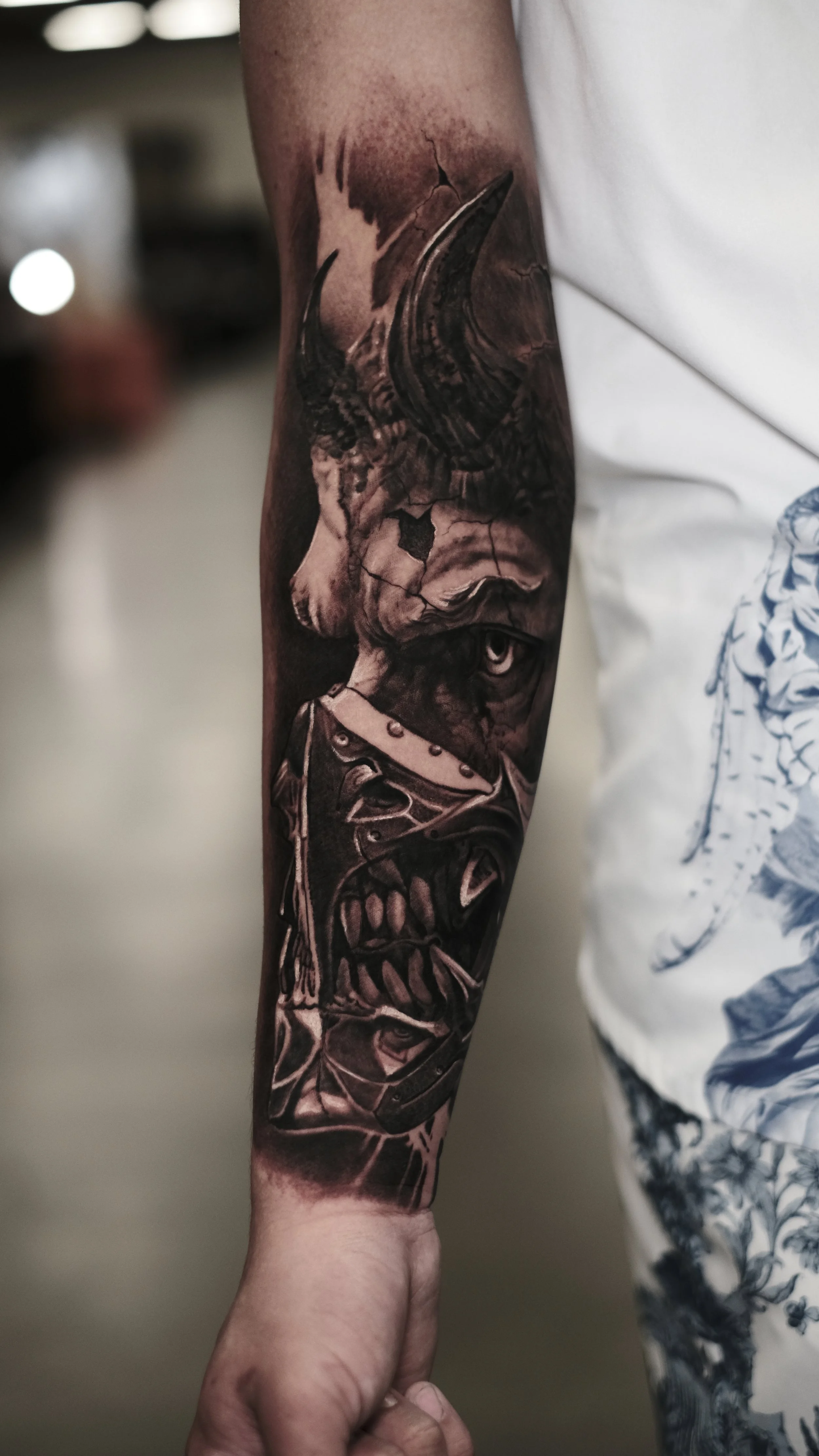 Black and gray realistic tattoo of a dinosaur skull on a person's arm.
