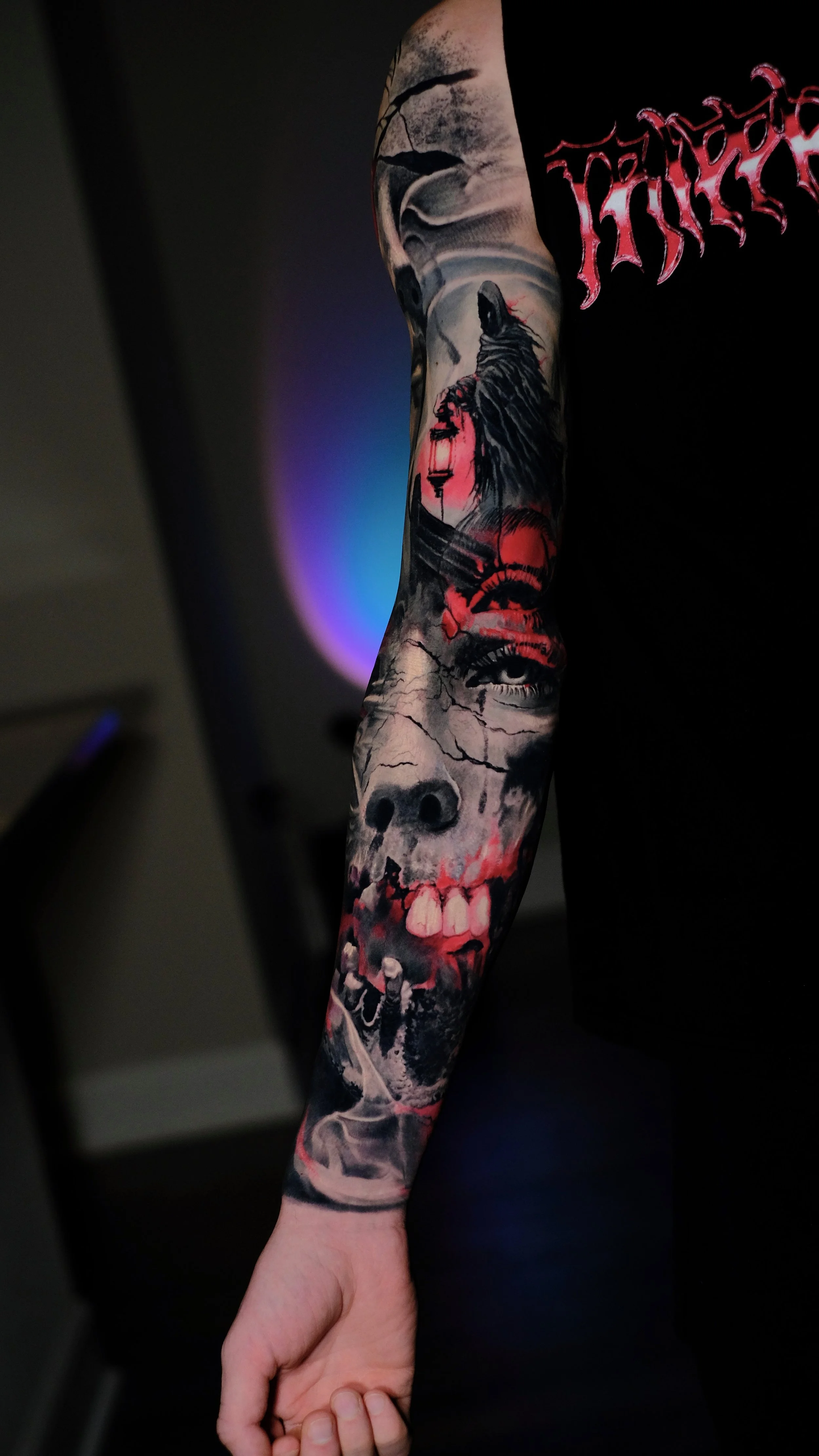 Detailed full sleeve tattoo on a person's arm featuring a skull, a crow holding a lantern, a serpent, and an eye, with red and black ink in a realistic style.
