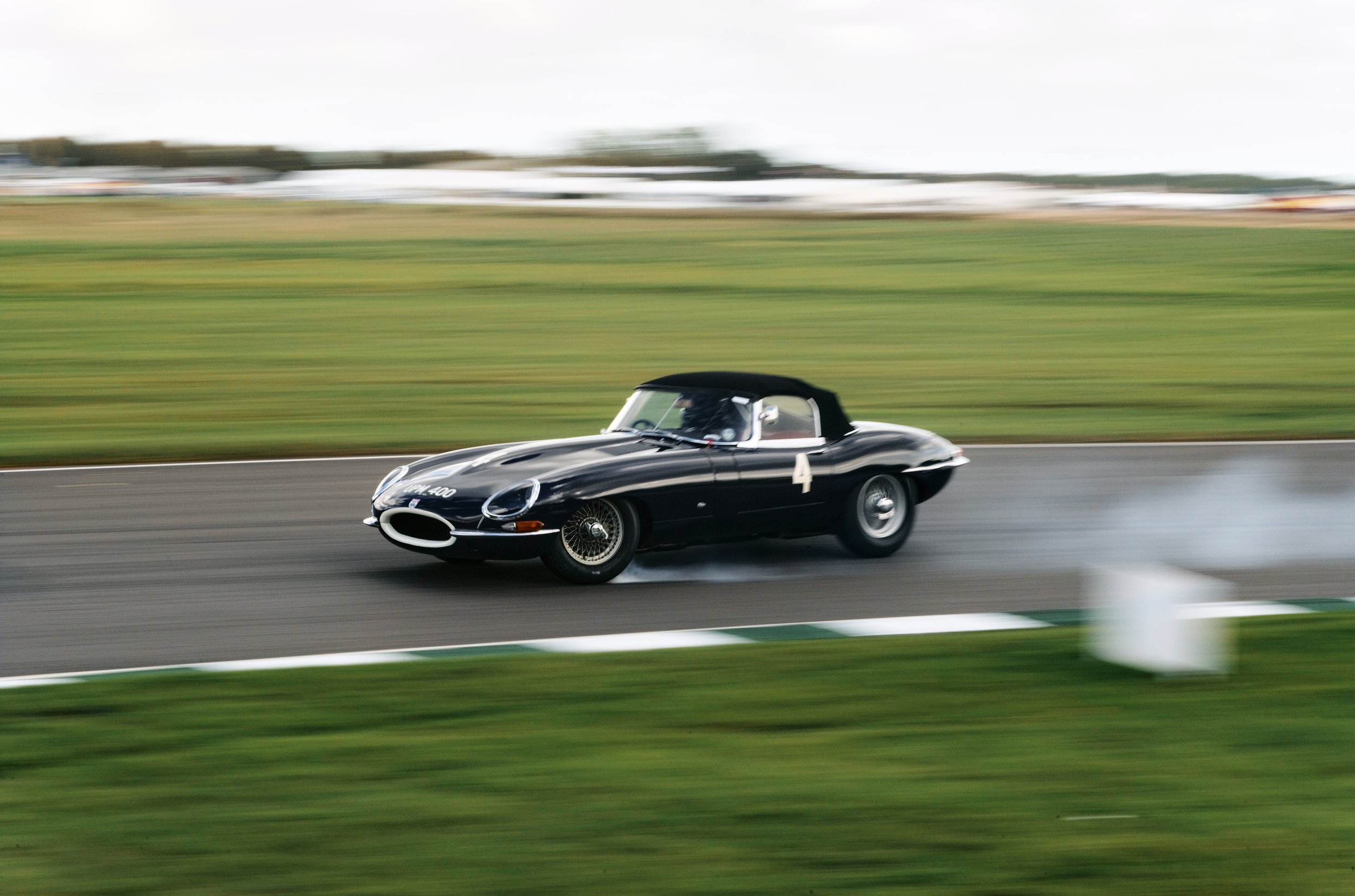 A black vintage race car speeding on a racetrack with motion blur background.