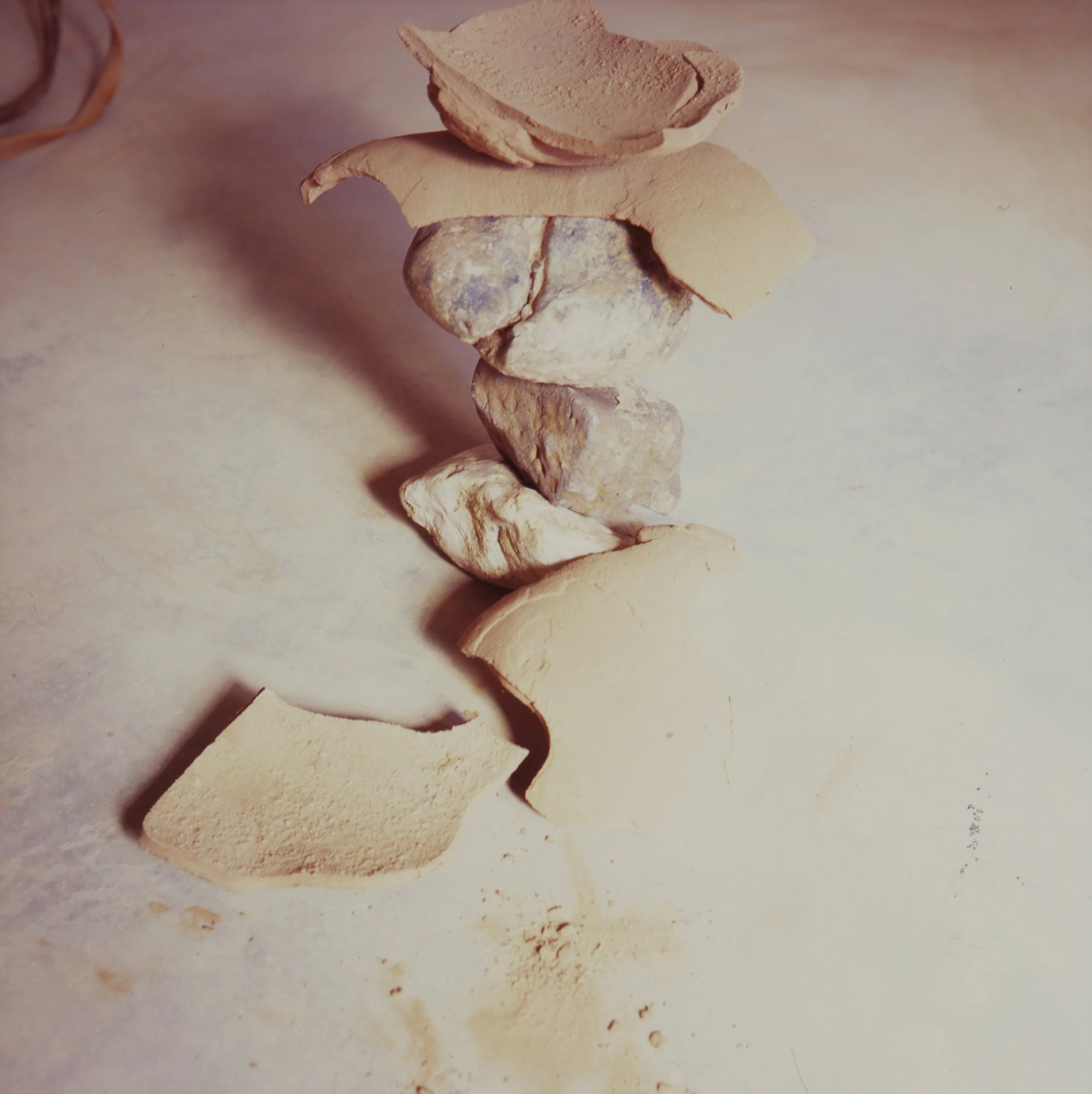 A pile of broken clay pieces with a shattered bowl resting on top, showcasing the fragments and texture of the materials.