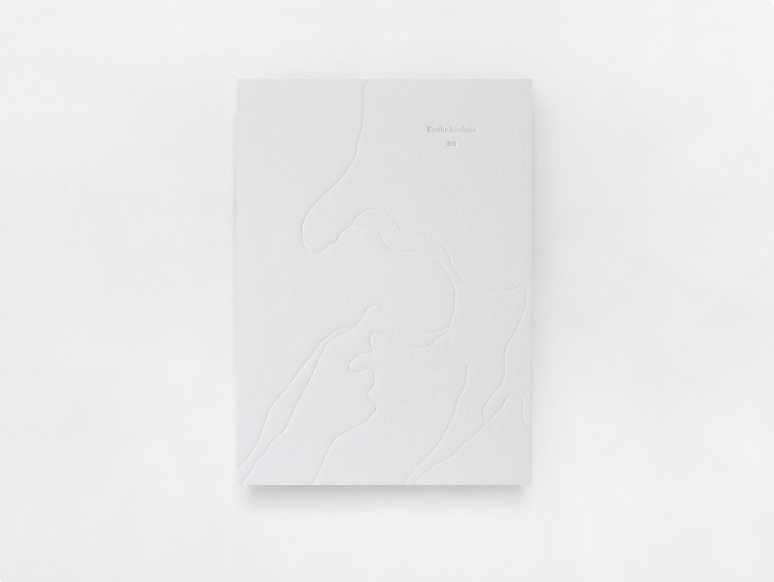 A white notebook with a colorful drawing on its cover, positioned on a table.