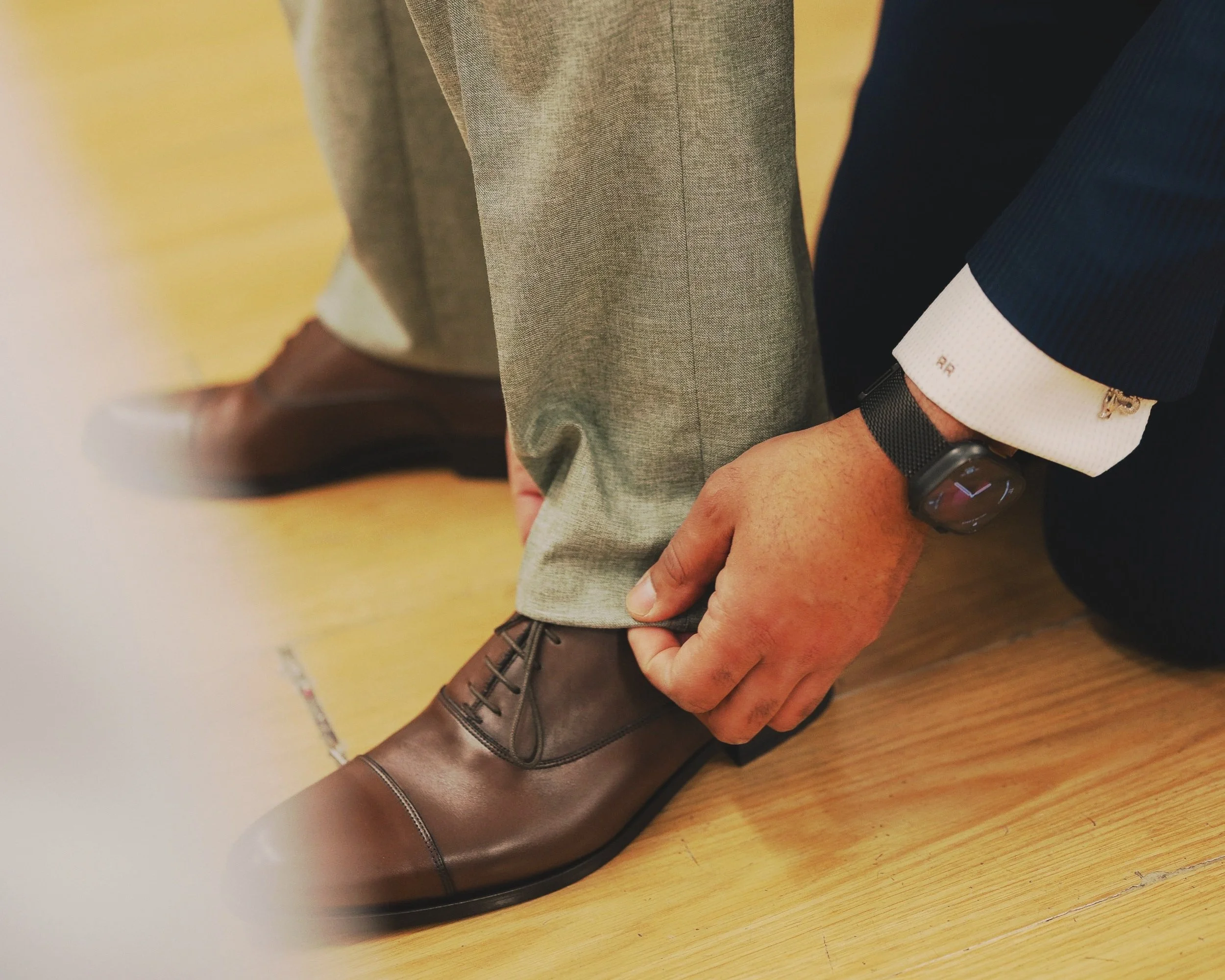 Bespoke Tailor Roberto Revilla Adjusting The Hem Of A Client's Suit Trouser Leg.