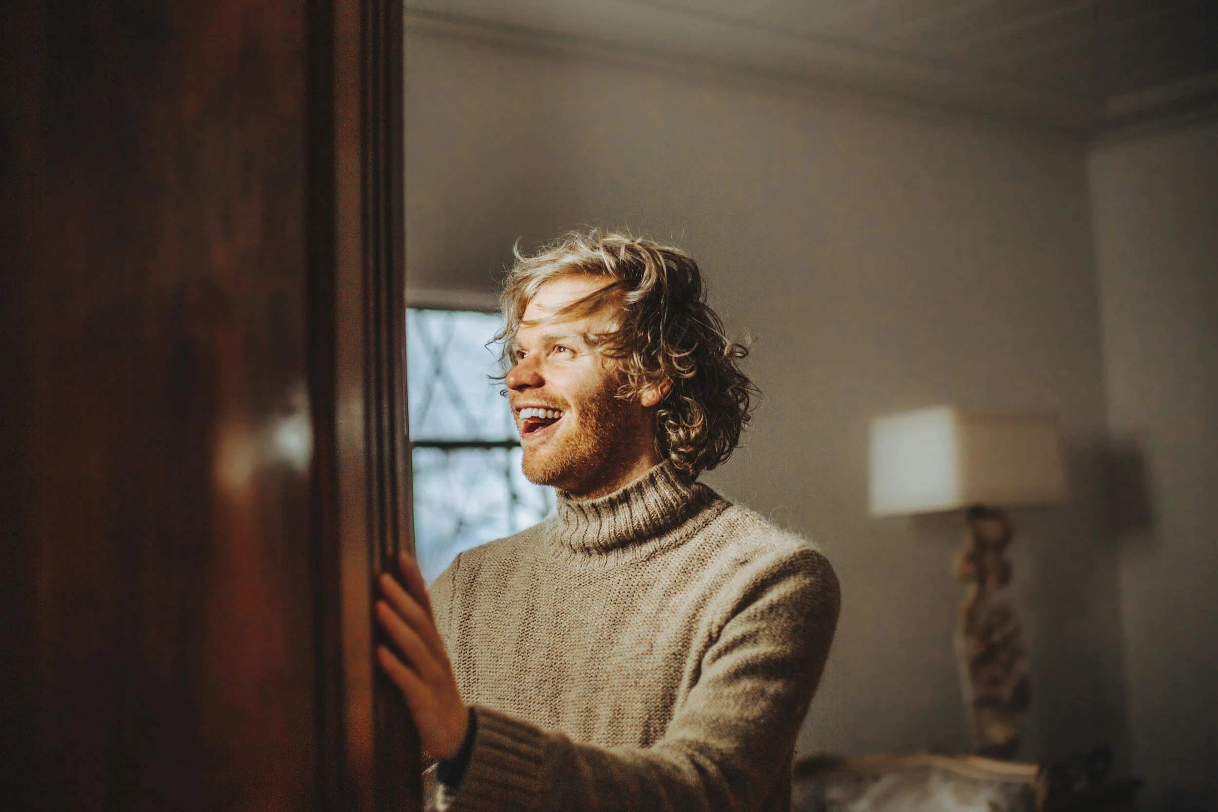 A man opening a closet that is uncluttered and organised, smiling with joy