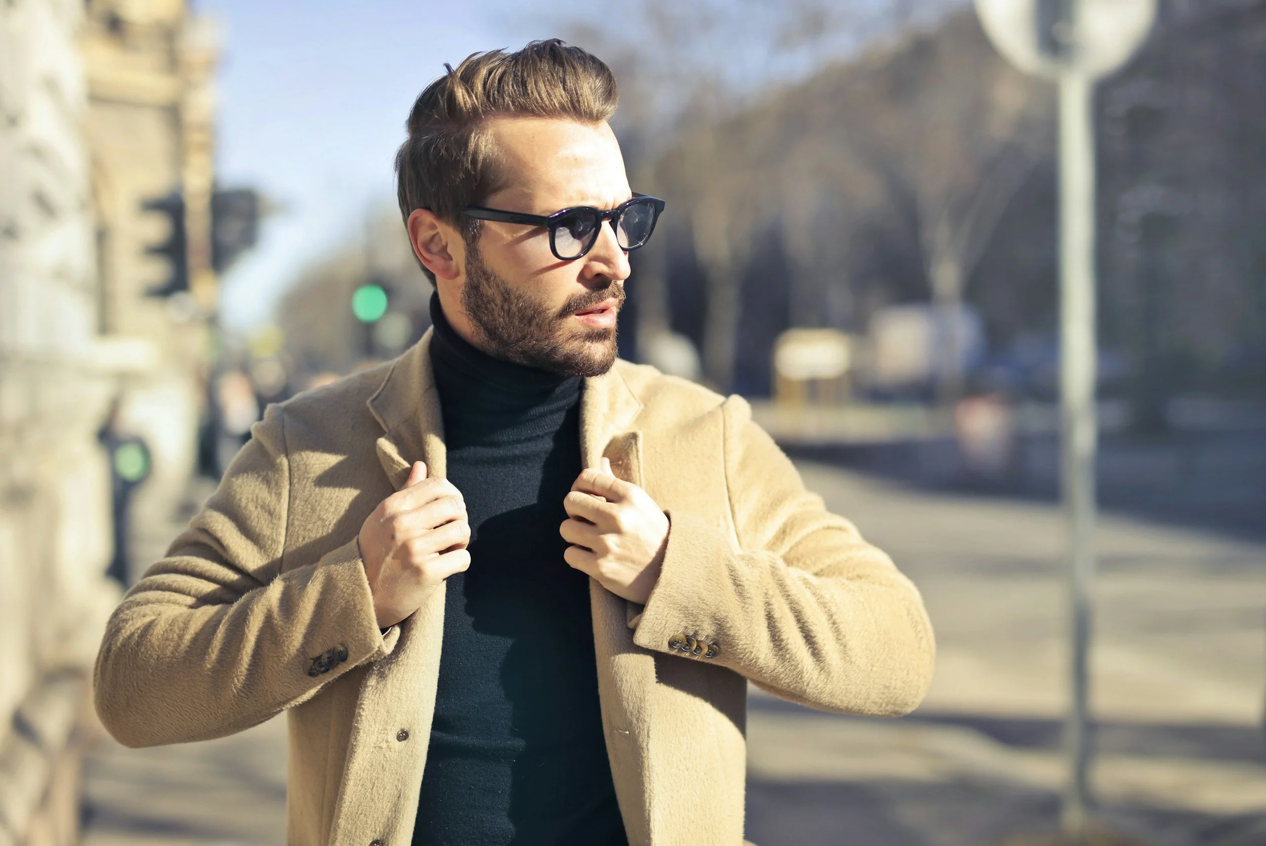 a man with designer glasses on a cold winter's day in London, wearing a roll neck sweater and cashmere coat as part of a smart casual outfit