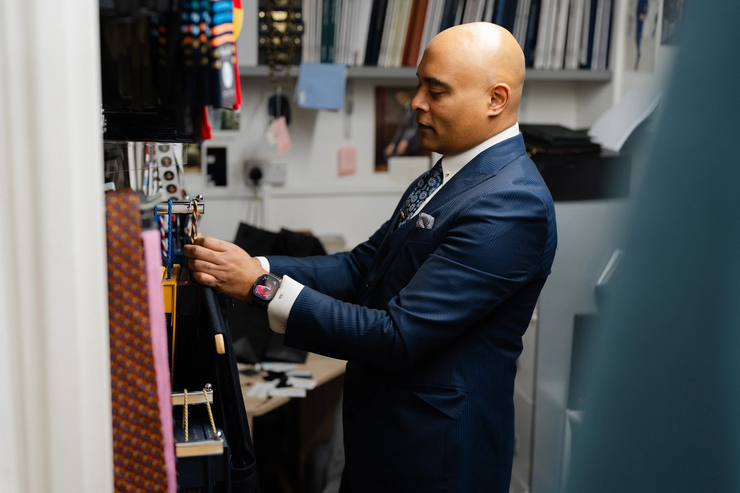 London Bespoke Tailor Roberto Revilla at his workroom in Tottenham Court Road, wearing a three piece single breasted peak lapel navy self stripe suit with white bespoke shirt and woven tie.