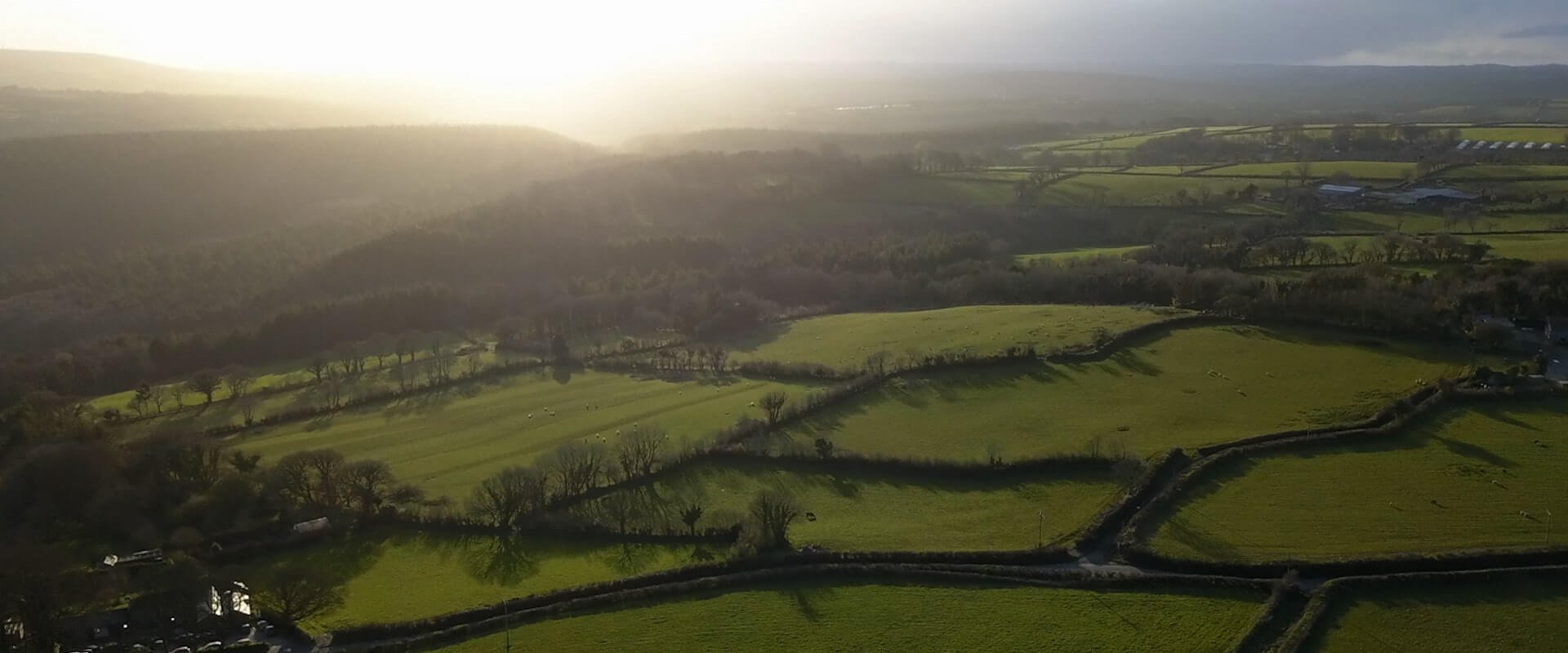West facing Aerial drone shot facing farmers fields with a golden sunset