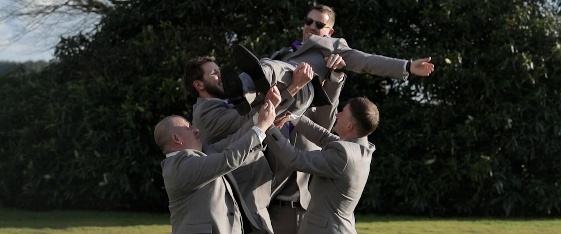 The Grooms men collectively throw Alex into the air and catch him again