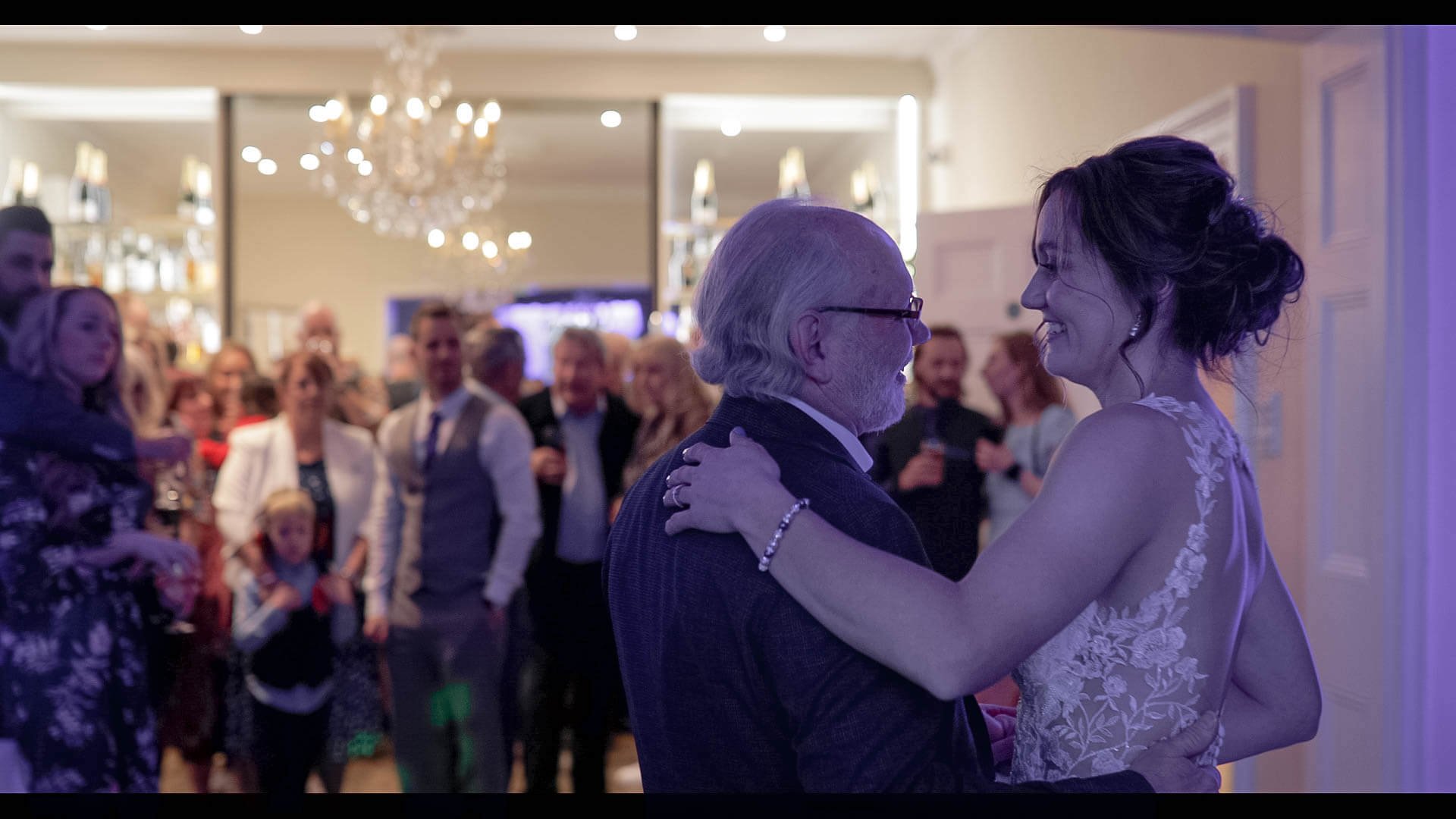 Zayna and her Father hold each other during the Father/Daughter wedding dance in front of the wedding party.