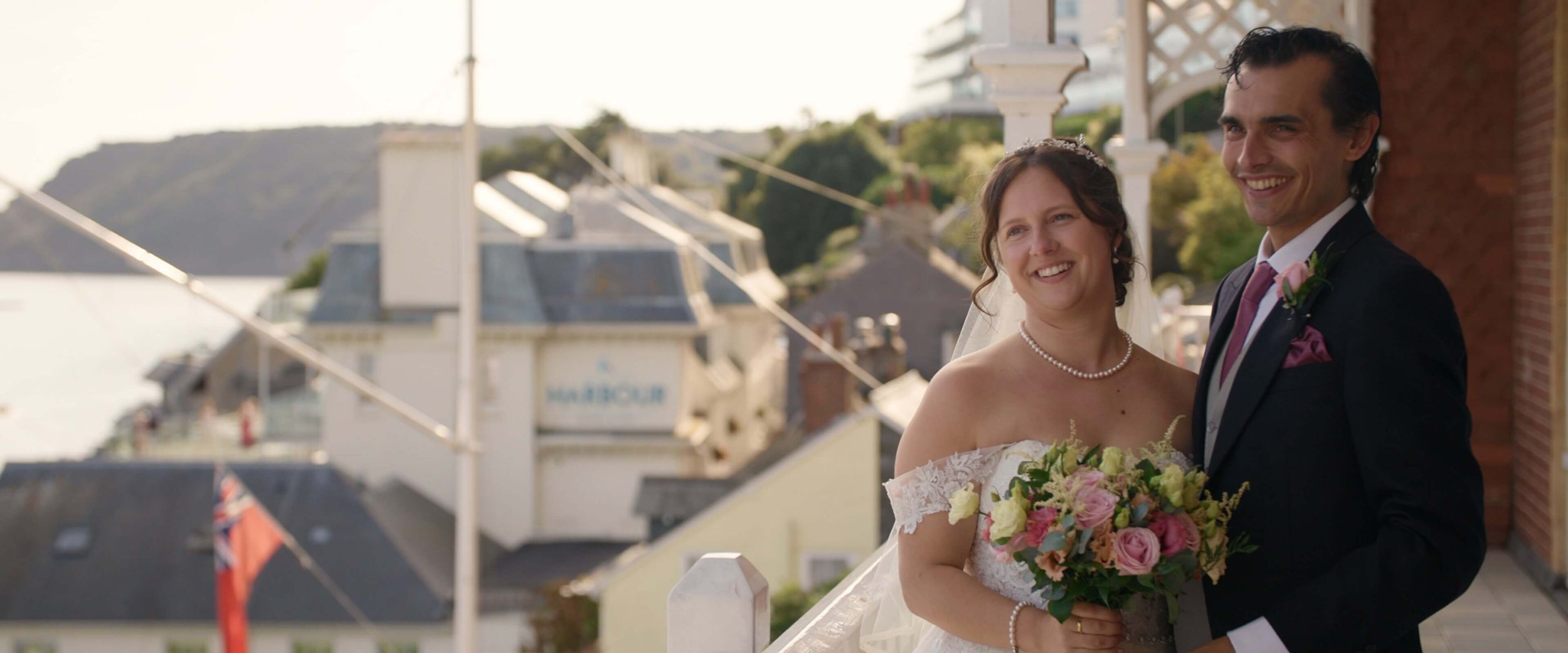 Amy &amp; Stephen hold each other and smile for wedding photos on the Cliff House Hotel Balcony