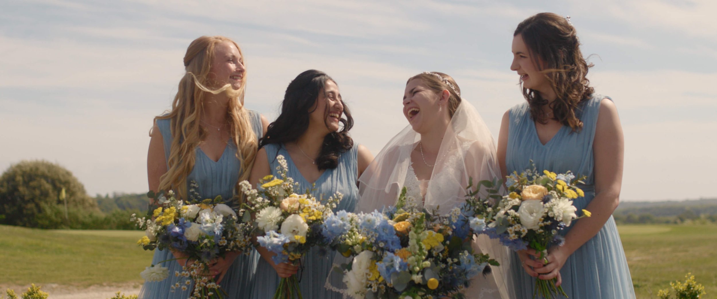 Bridesmaids looking at each other and laughing whilst holding their wedding bouquets for wedding photos