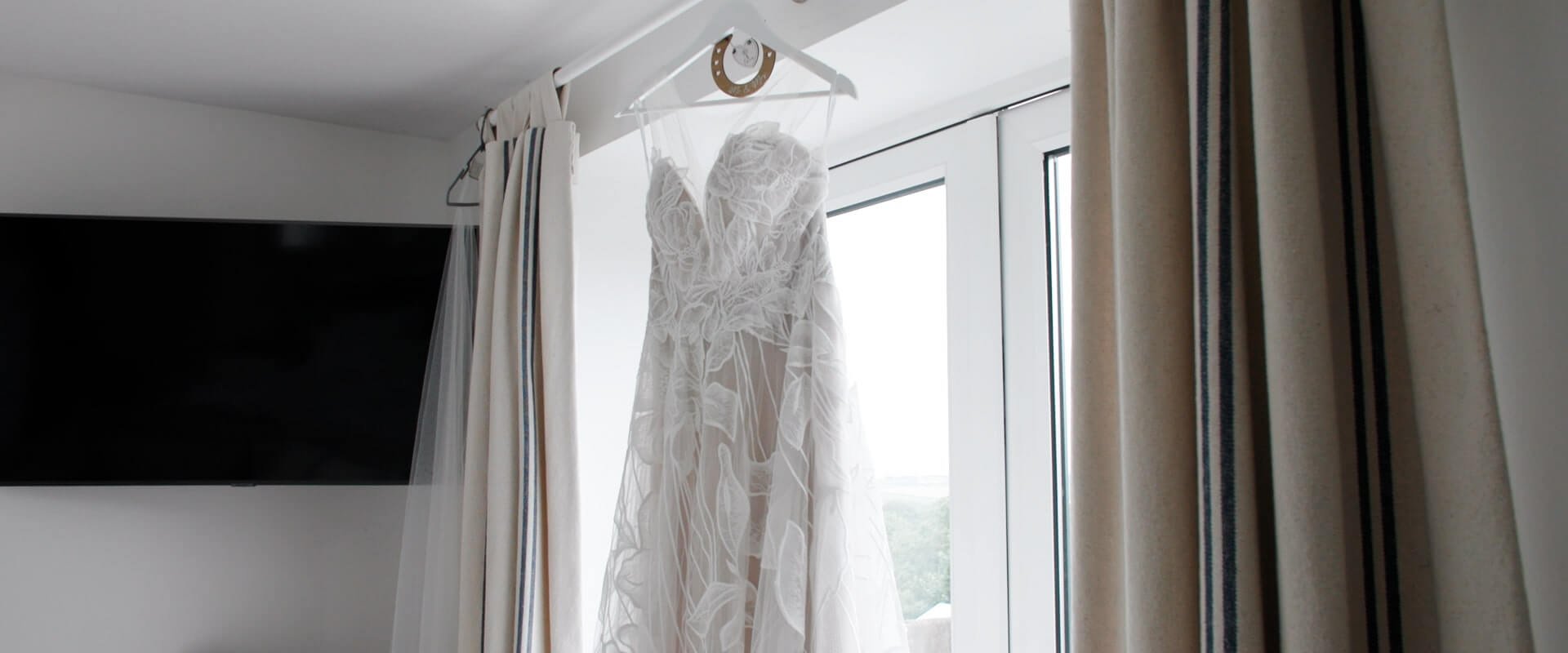 Stunning wedding dress hangs from the window inside The Gate's bridal cottage