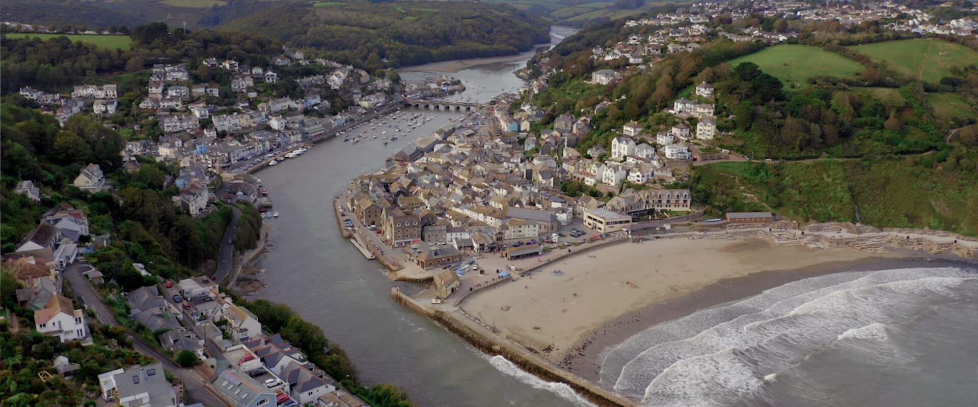An Aerial drone shot of East Looe Beach, including Looe Harbour and the Sardine Factory
