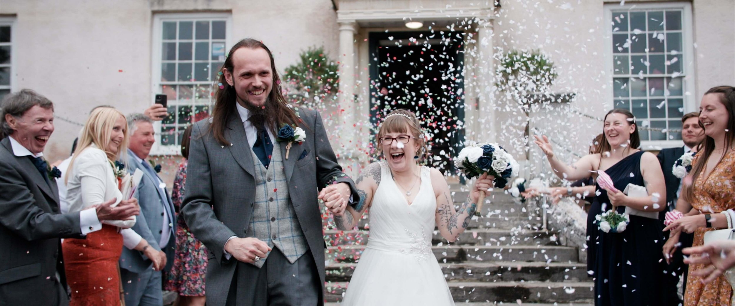 Candice and Colin laugh and cheer as they reach the end of the confetti line in front of Torre Abbey