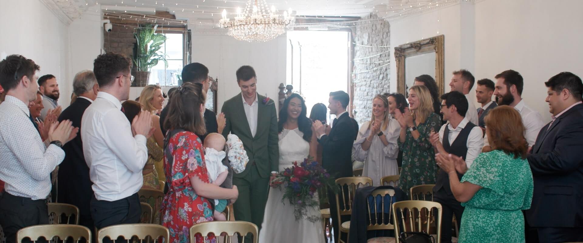 The wedding guests erupt in cheers as Rita and Michael enter the wedding ceremony together