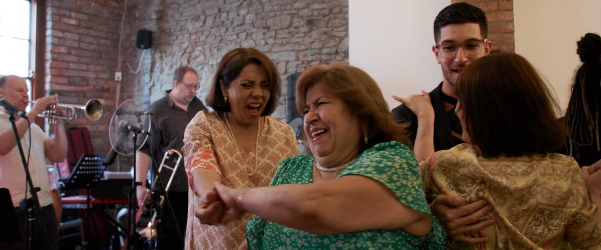 Rita's mother laughing whilst dancing with her sister during the wedding party