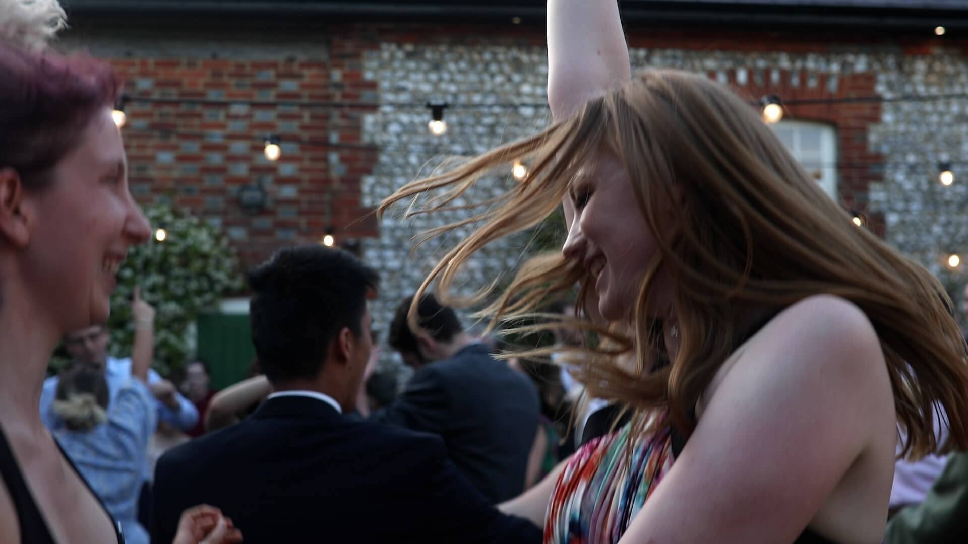 Redhead woman enjoys dancing at the wedding party with her arm up in the air