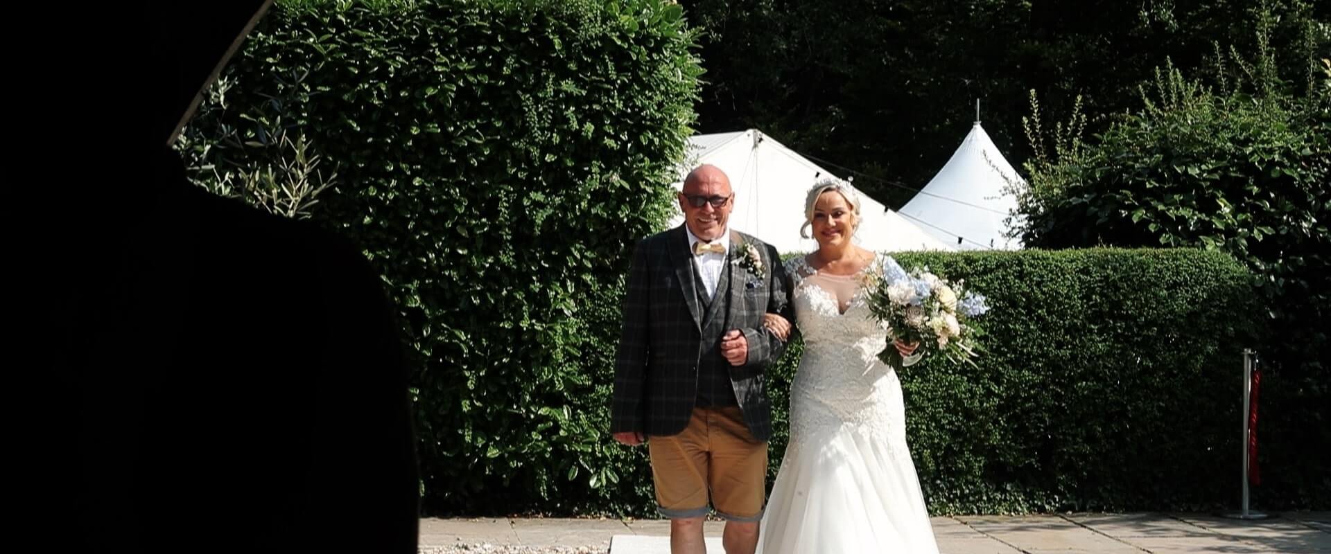 Terell walks down the Aisle with her father, who is wearing chino shorts.