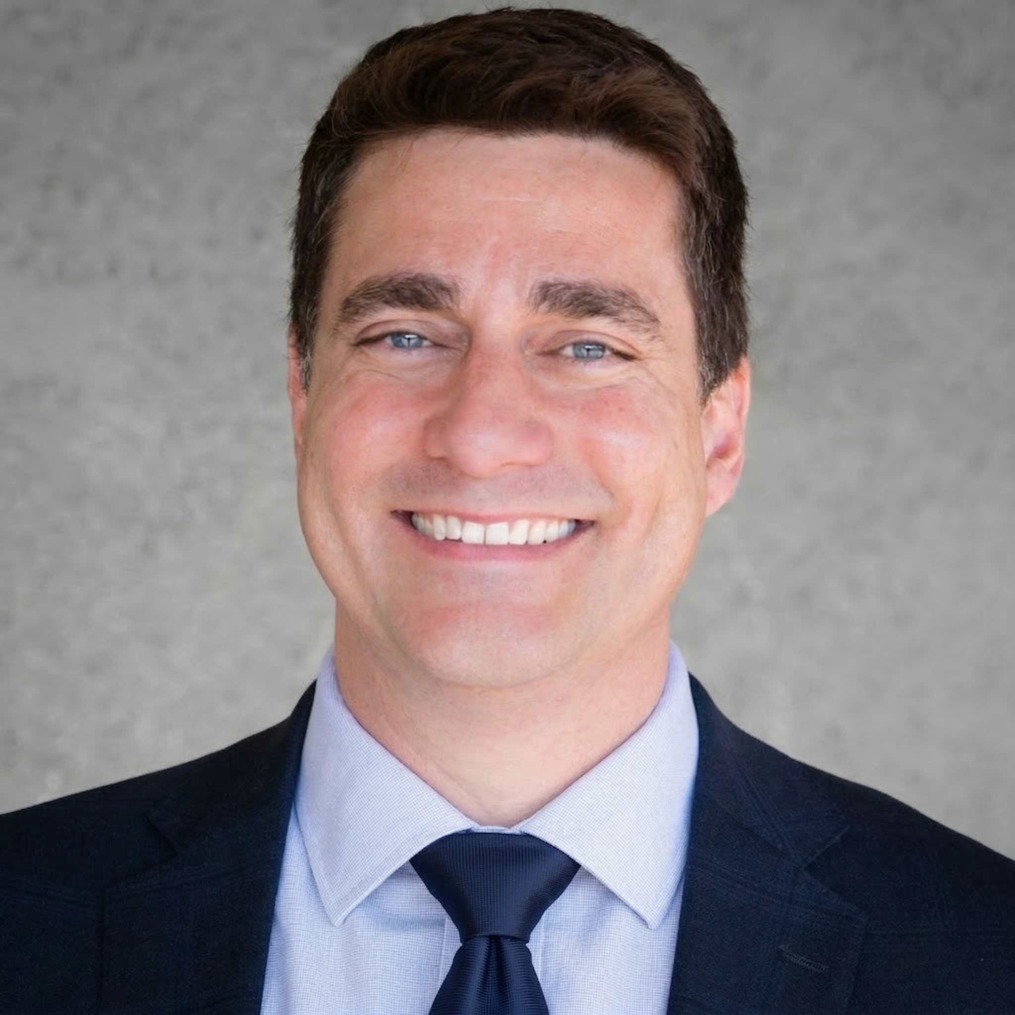 Dave Moniz is smiling and wearing a blue suit.