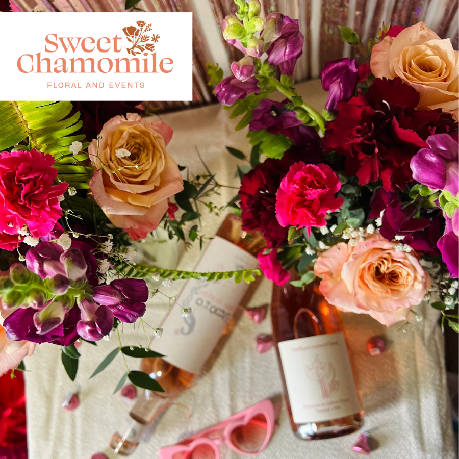 Two colorful floral bouquets with a bottle of wine and heart shaped festive sunglasses.