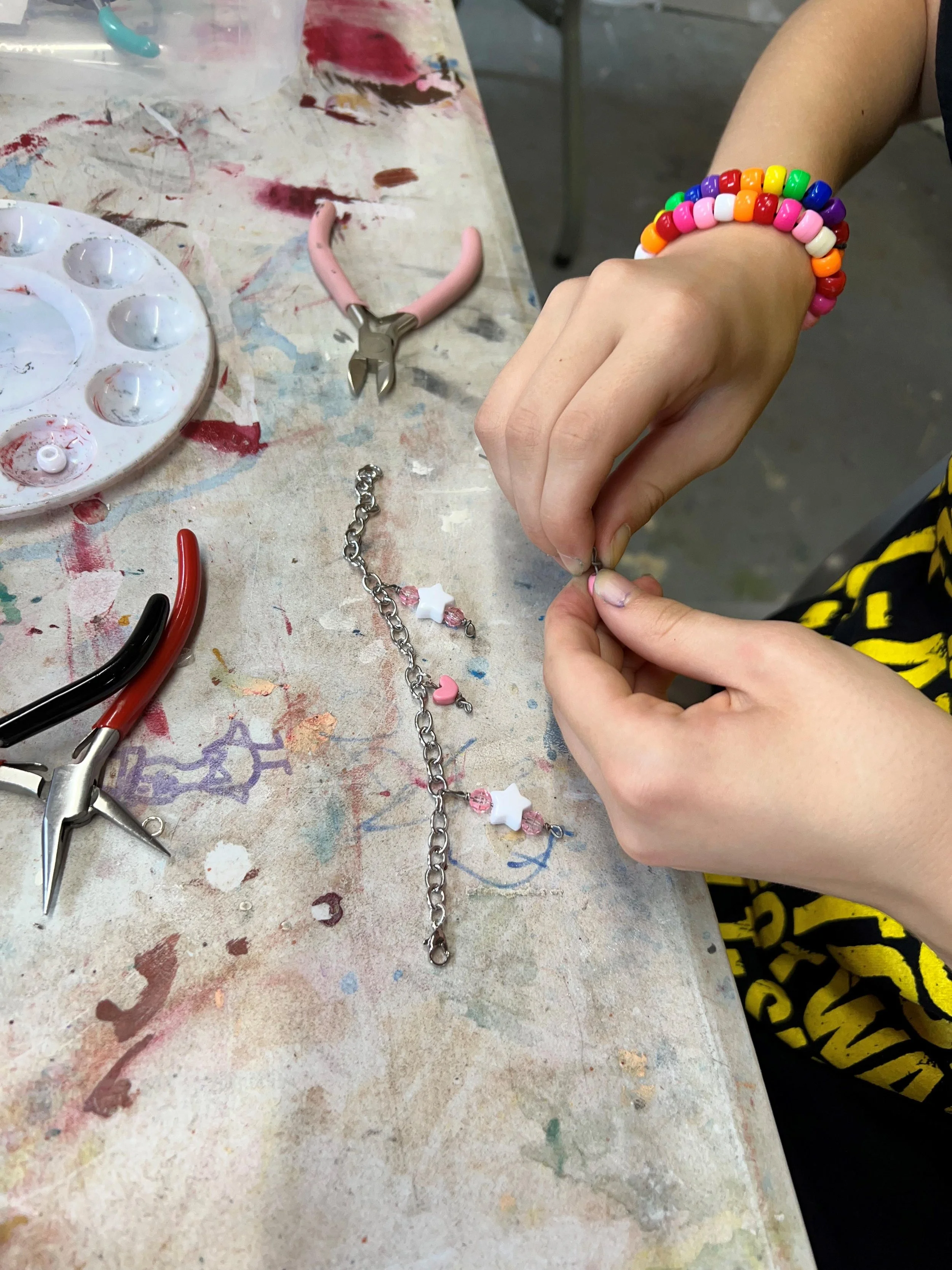 hands with pliers creating a bracelet with upcycled materials