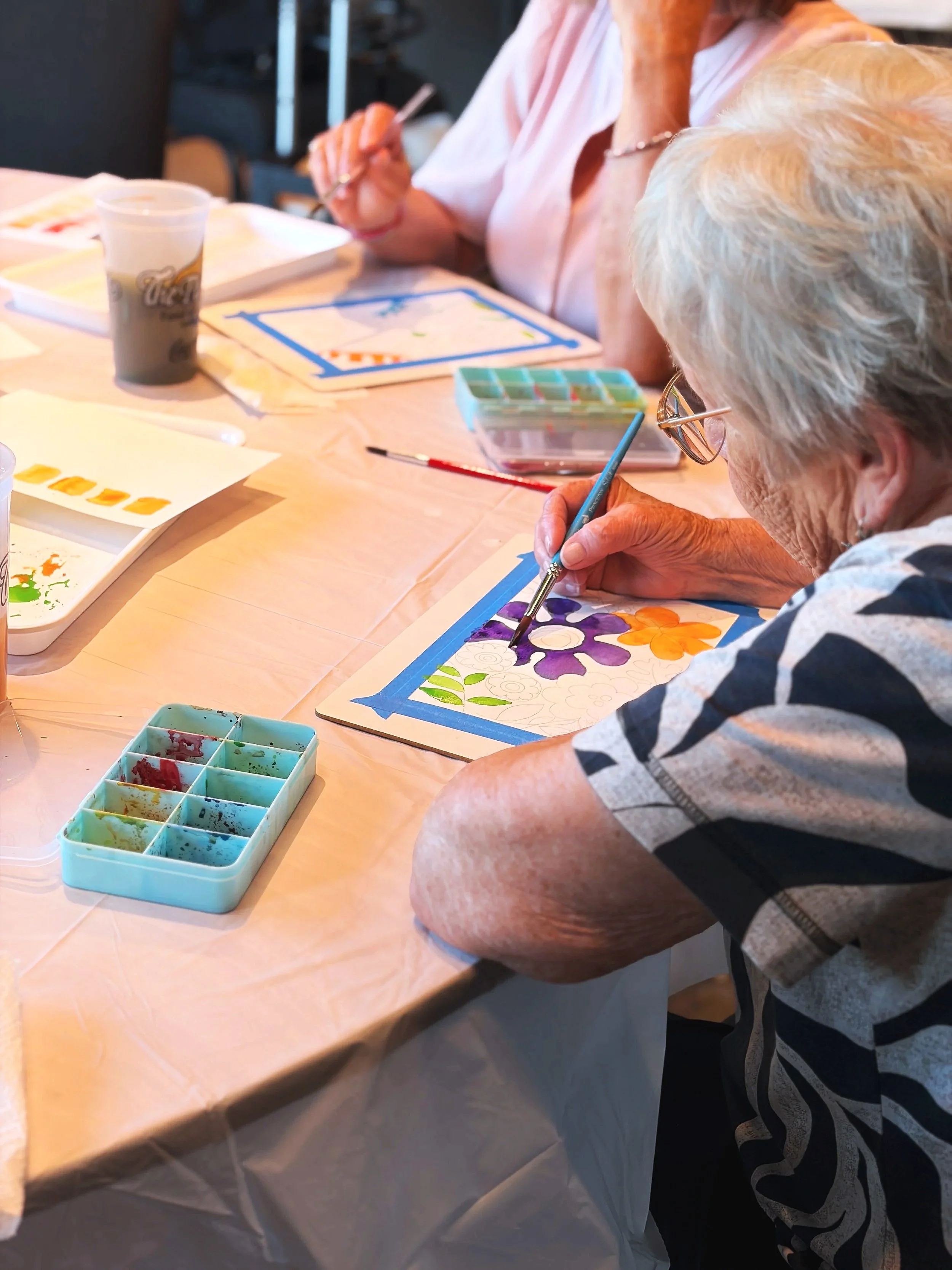 Older lady painting a purple watercolor flower