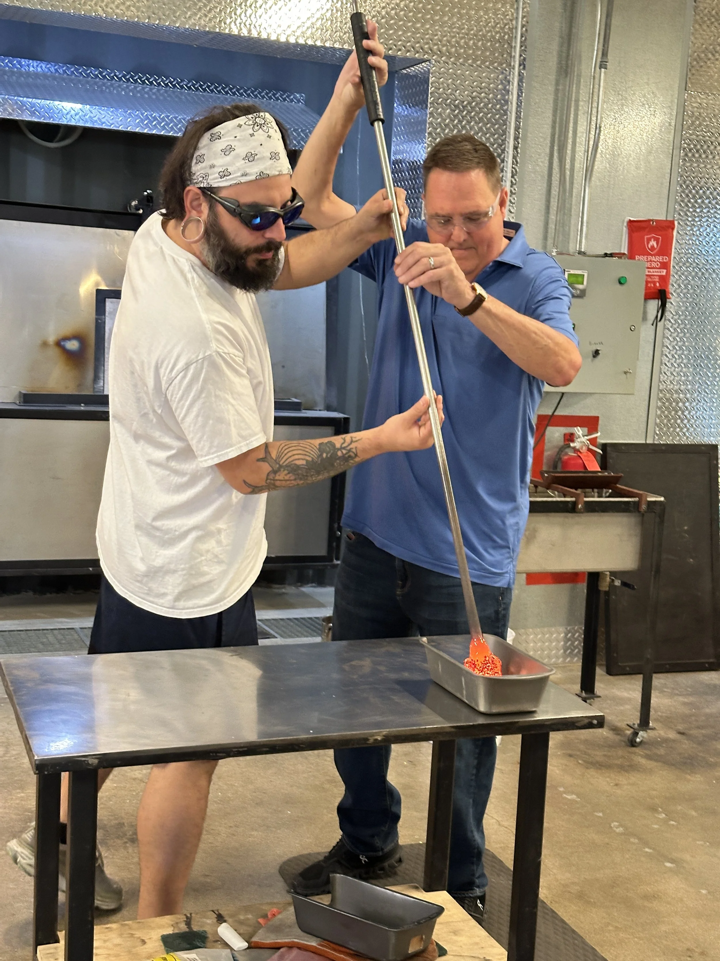 Student and instructor demonstrating a technique during a glass blowing class 