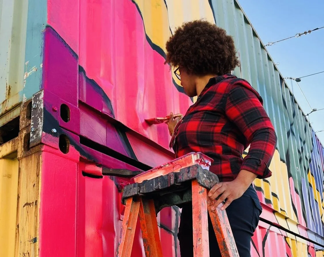 african american woman painting a mural 