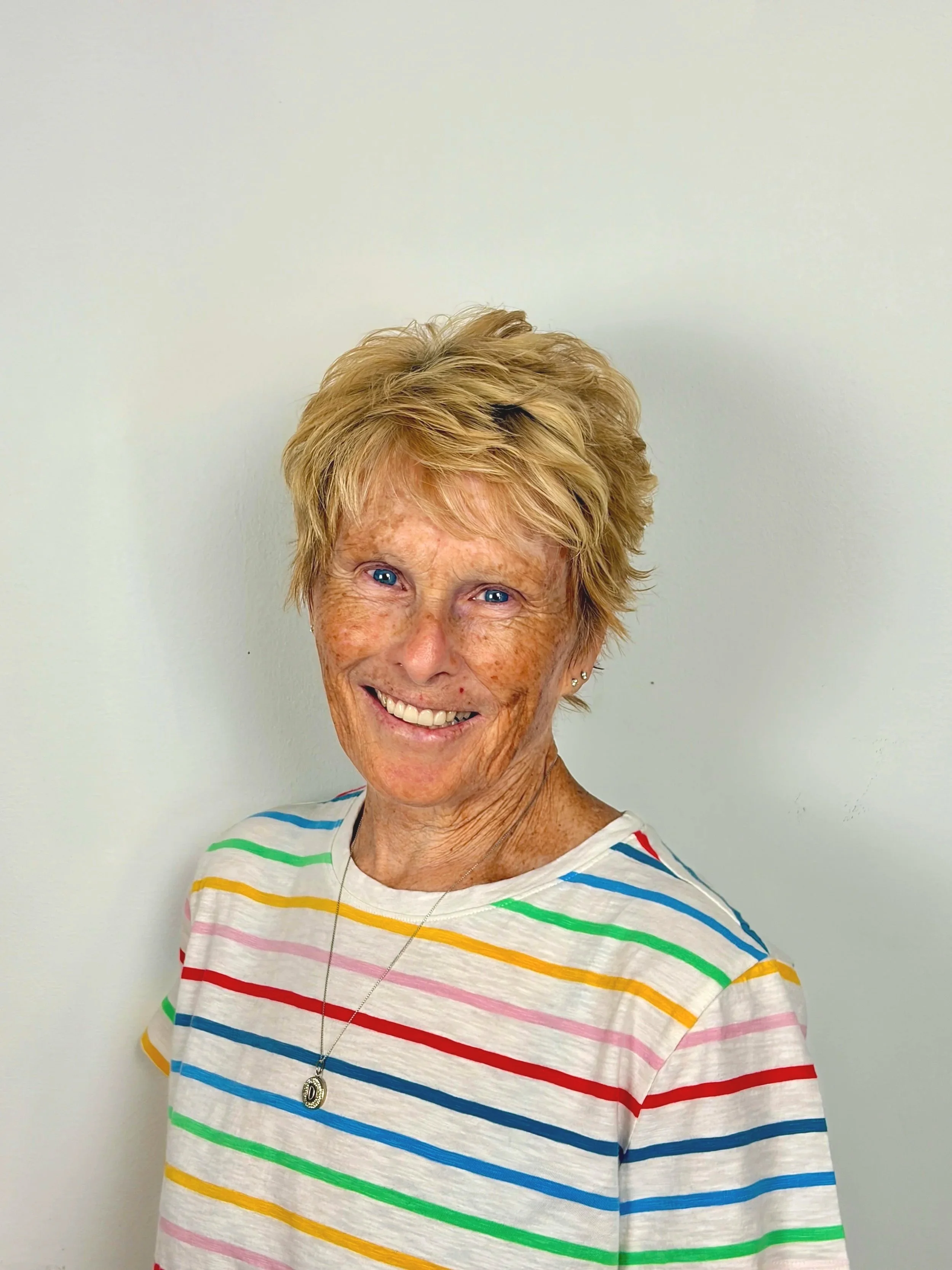Older lady smiling wearing a striped shirt