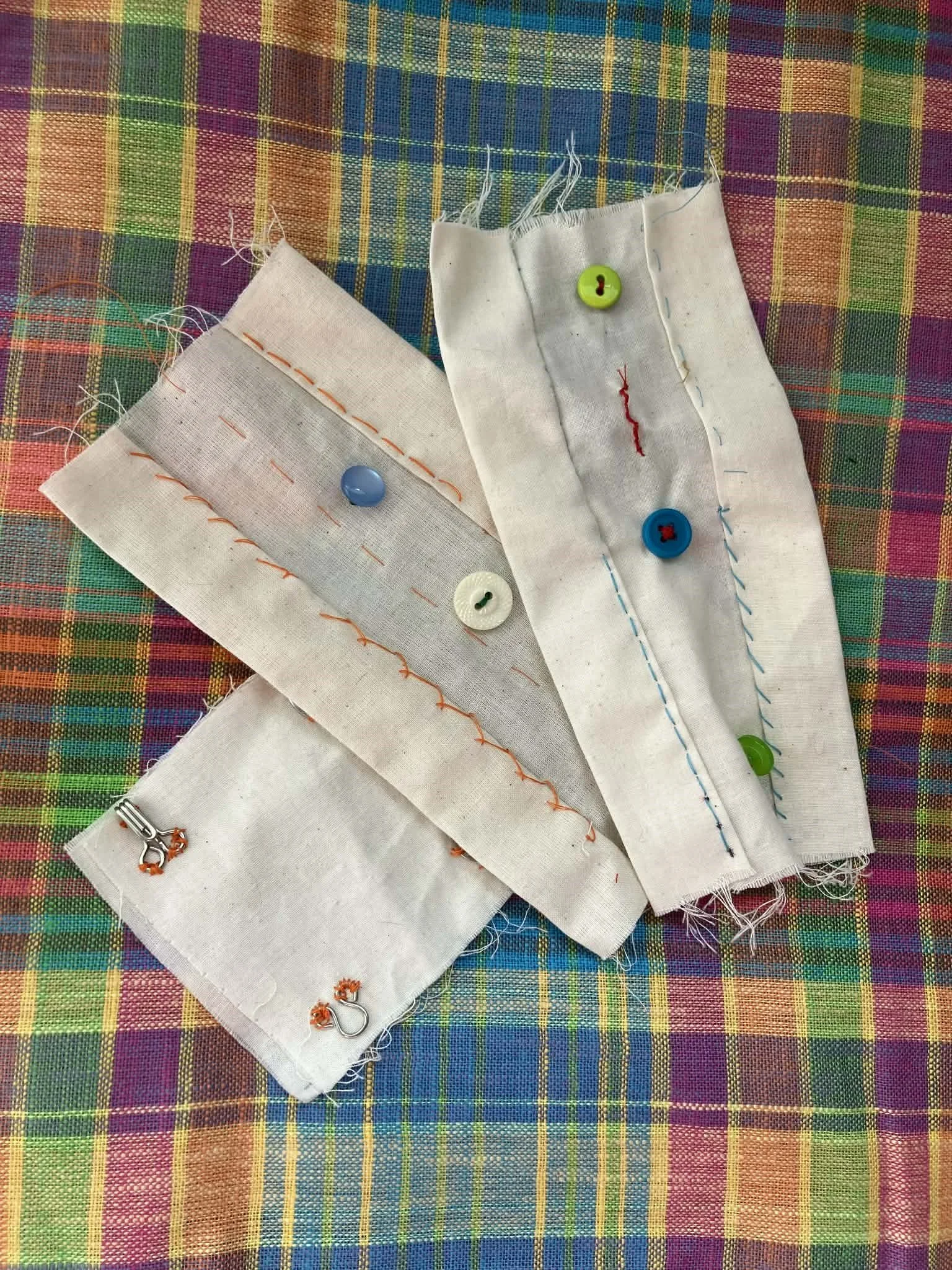 Various muslin projects with various stitches and buttons on a colorful, plaid background