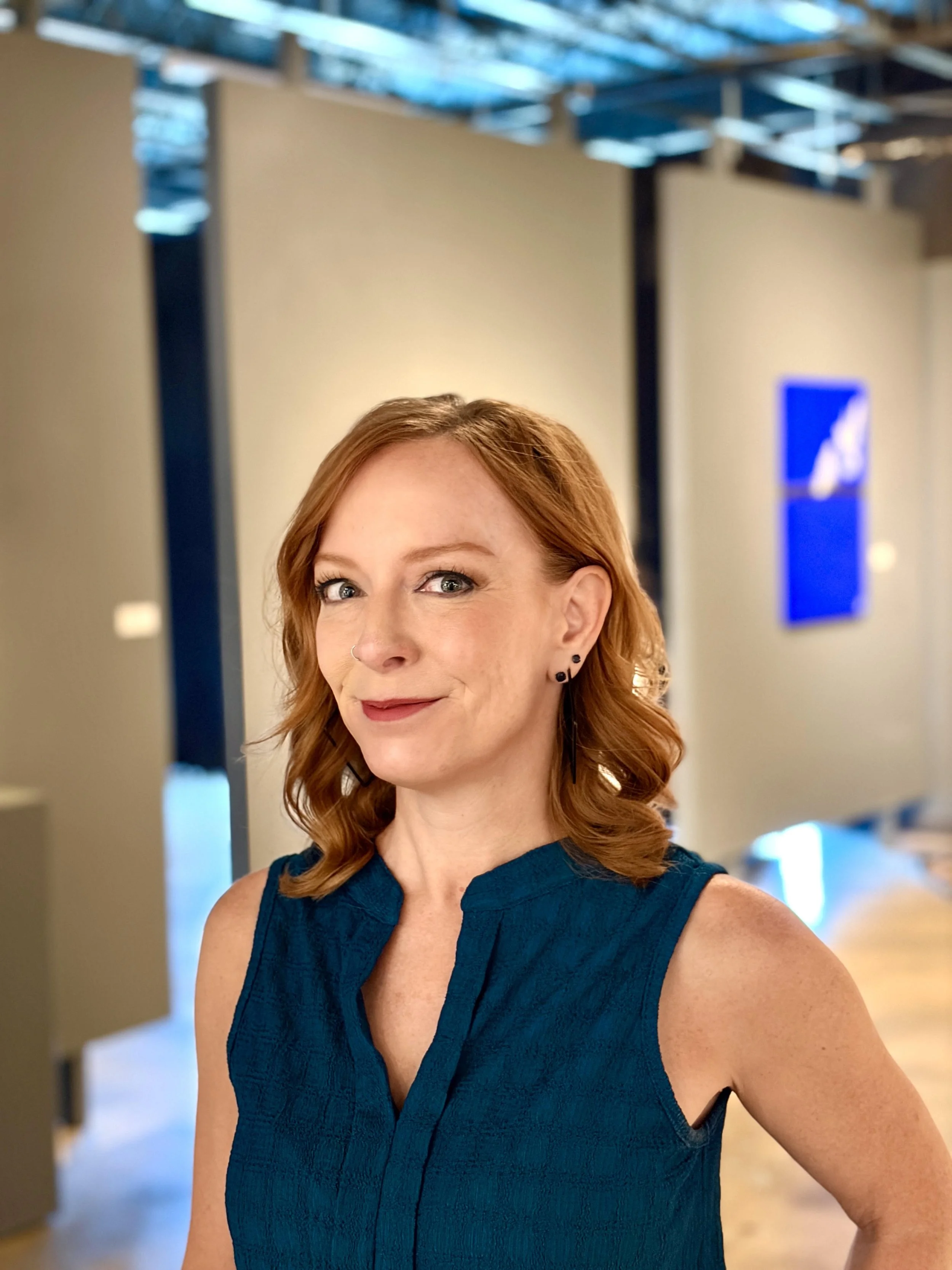 Red haired woman with a blue shirt smiling