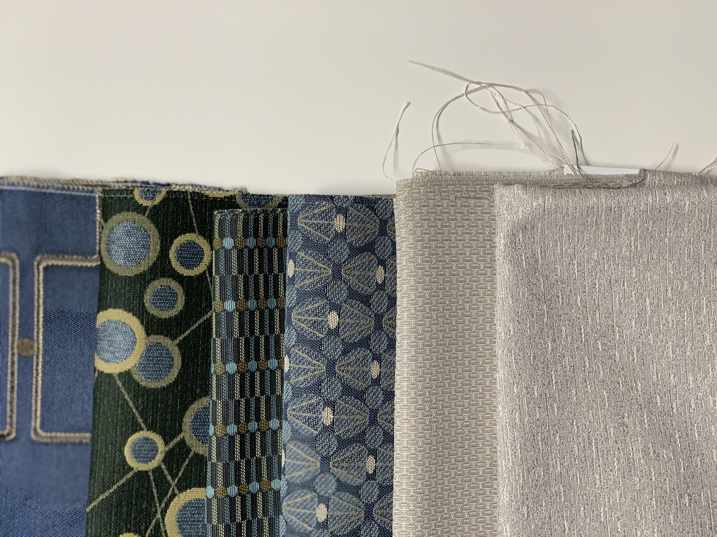 Six fabric swatches with various blue, green, gray, and metallic patterns and textures, arranged vertically.