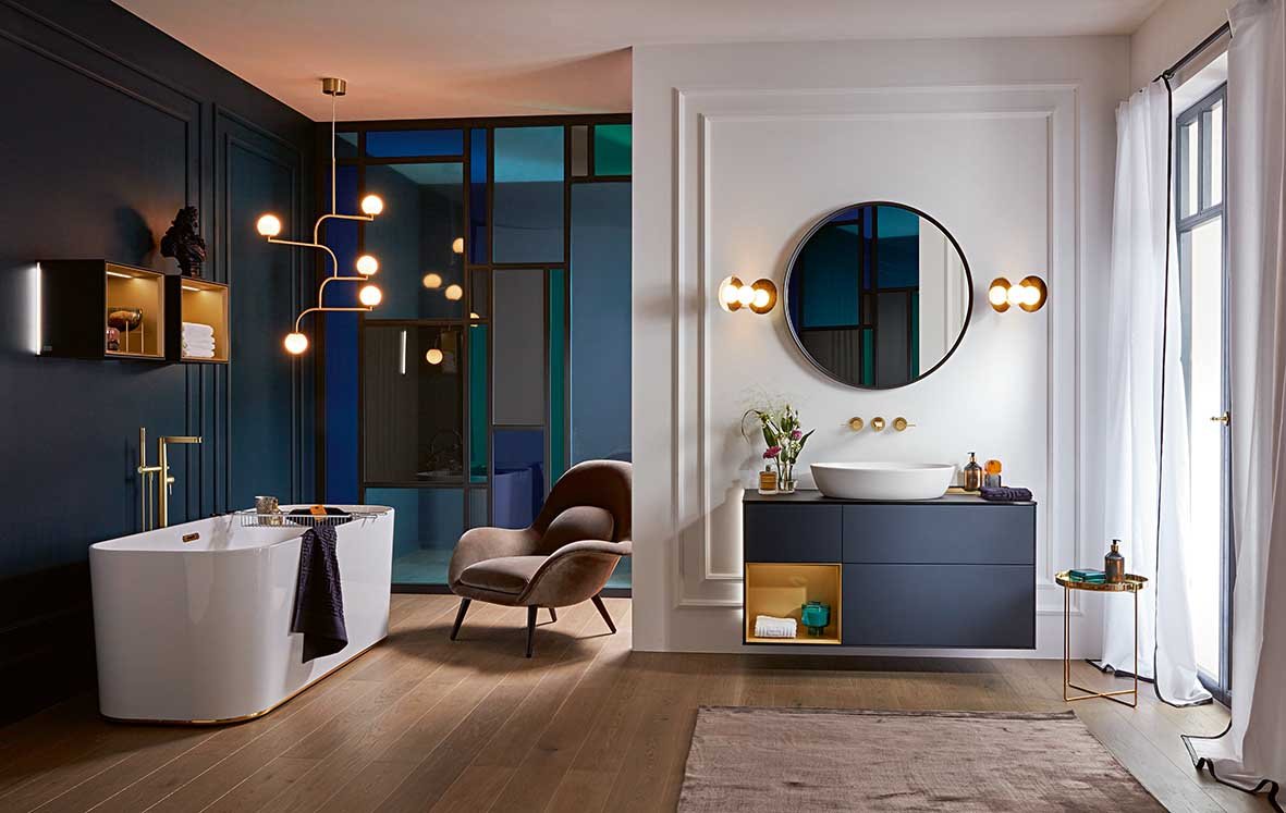 a luxe blue and cream bathroom with freestanding bath and floating vanity unit with round mirror above