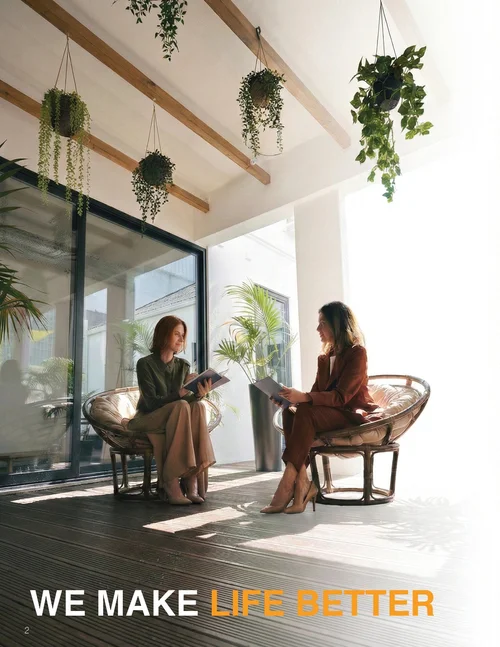 Two people in conversation on a sunlit terrace, with the line We make life better