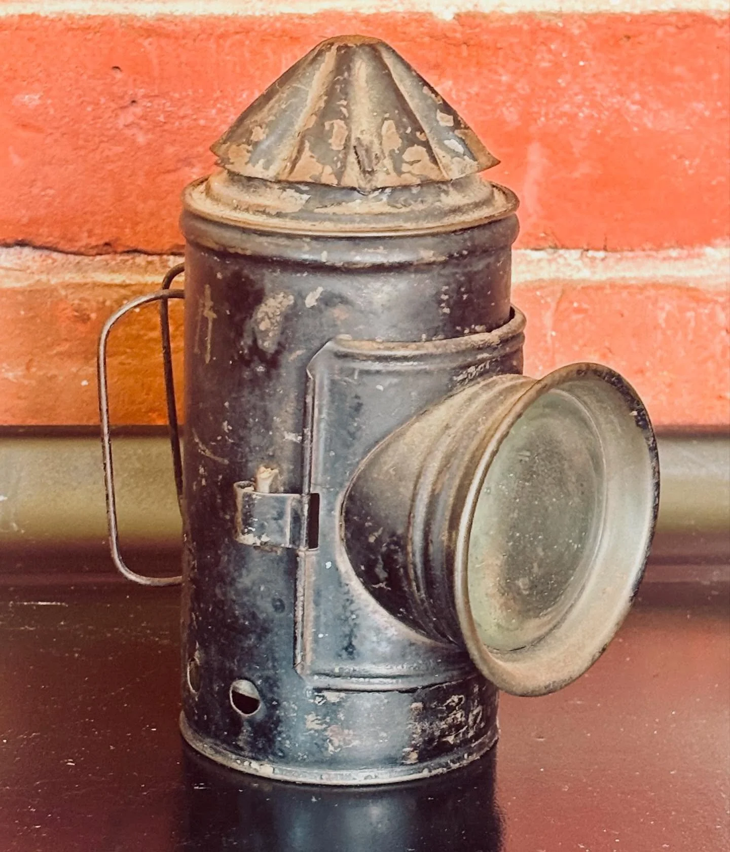 This bullseye oil lantern once lit the way for someone making the rounds&mdash;perhaps a night watchman, or an early patrol officer pacing quiet streets before flashlights existed.

Its clear convex lens magnified flame into clarity, while the red an