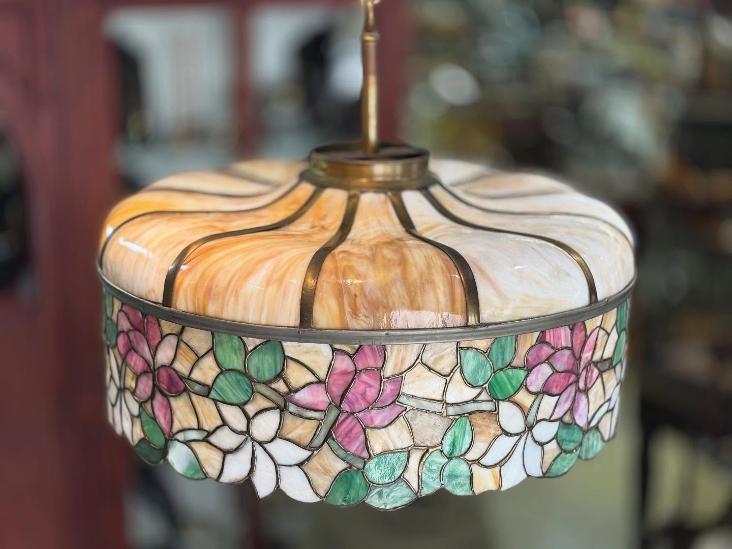 A beautifully crafted hanging lamp with richly colored, stained glass in a floral design. The shade glows, warmly when lit, casting soft light that brings real atmosphere to a space. It&rsquo;s generous scale gives a presence that feels both grounded